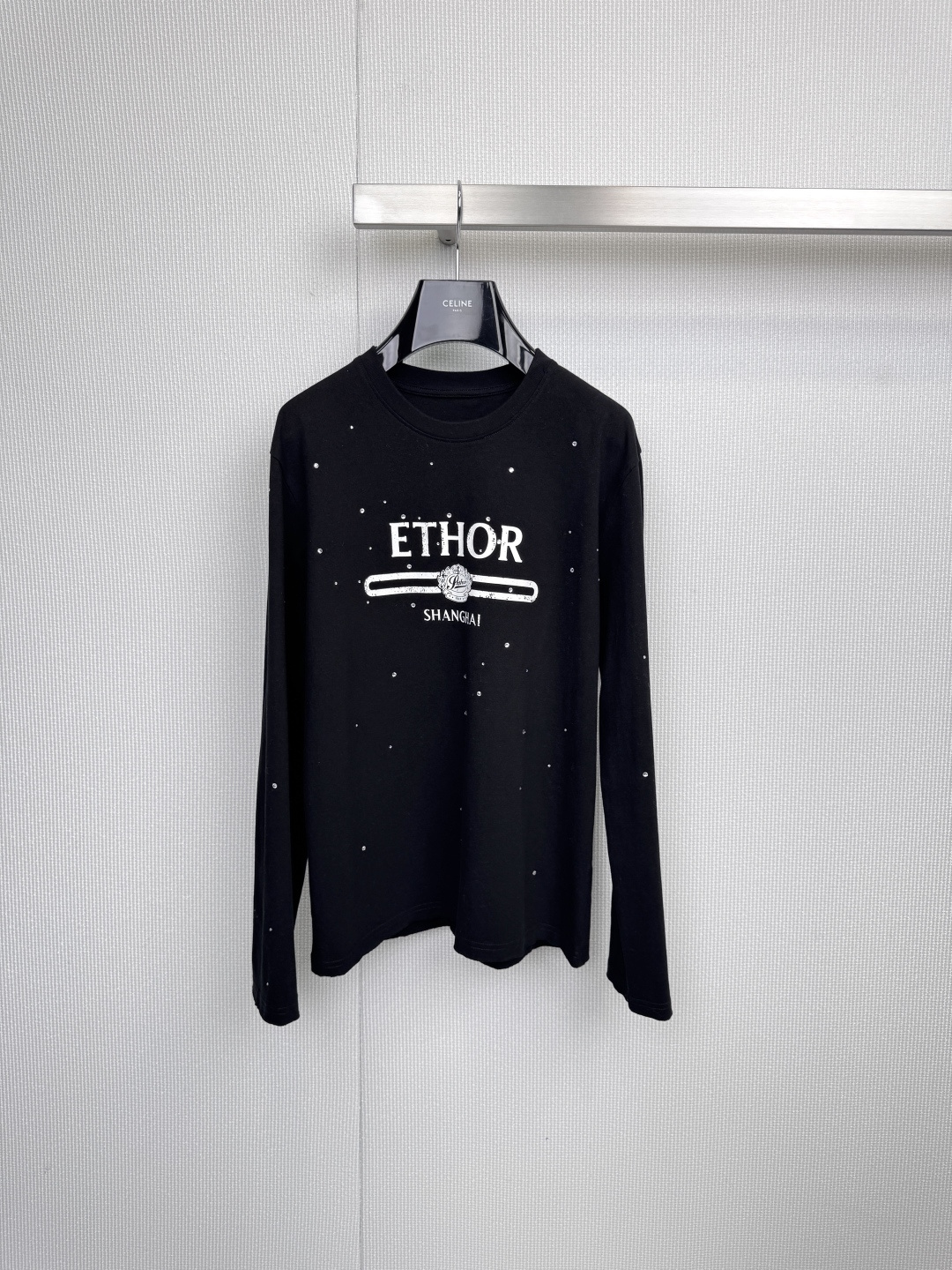 NO:590508,ETHOR long-sleeved T-shirt, urban minimalism, hidden edge, black and white solid color base interprets timeless classics, this ETHOR long-sleeved T-shirt conquers the urban wardrobe with neat tailoring and secret details, 'ETHOR' on the chest  The 'SHANGHAI' logo connects the tension between the brand and the city with a horizontal line, and the exquisite pattern embellished on it is like Morse code, hiding design ingenuity - it is both a visual focus and a metaphor for identity. The white model is covered with fine silver sequins, and the light flows like stars and diamonds quietly shining, injecting low-key luxury into daily wear. The black model uses a matte texture to settle a calm aura, and the dark pattern details inadvertently reveal the pursuit of quality, 19  The year of birth of the brand 68 is imprinted on the corner of the clothes, silently telling the fusion of historical heritage and contemporary style. From the hanging aesthetics of the silver clothes hanger to the crisp drape on the upper body, every aspect demonstrates ETHOR's dedication to materials and craftsmanship. It is simple and uninhibited when worn alone with jeans, and can also be layered with a suit jacket. This T-shirt is not only a universal cornerstone in the wardrobe, but also a visual poem written for Shanghai's modern life. Size SML  P,,jeans,jackets & coats,tees,t-shirt,business suit,alexander wang19860909ETHOR长袖T恤,都市极简主义,暗藏锋芒,黑白纯色基底诠释永恒经典,这款ETHOR长袖T恤以利落剪裁与隐秘细节征服都市衣橱,胸前「ETHOR SHANGHAI」标识以一道横线串联起品牌与城市的张力,点缀其上的精致图案如摩斯密码般暗藏设计巧思——既是视觉焦点,亦是身份隐喻,白色款覆满细密银色亮片,光线流转间似星辰碎钻悄然闪烁,为日常穿搭注入低调奢华,黑色款则以哑光质感沉淀沉稳气场,暗纹细节于不经意间流露品质追求,1968品牌诞生年份烙印于衣角,无声诉说历史底蕴与当代风格的融合,从银色衣架的悬挂美学到上身时的挺括垂坠,每一处皆彰显ETHOR对材质与工艺的执着,单穿搭配牛仔裤简约不羁,内搭西装外套亦可叠出层次深度——这件T恤不仅是衣橱里的万能基石,更是写给上海摩登生活的一首视觉诗.码数SML P,,jeans,jackets & coats,tees，t-shirt,business suit,alexander wang,Women's clothing
