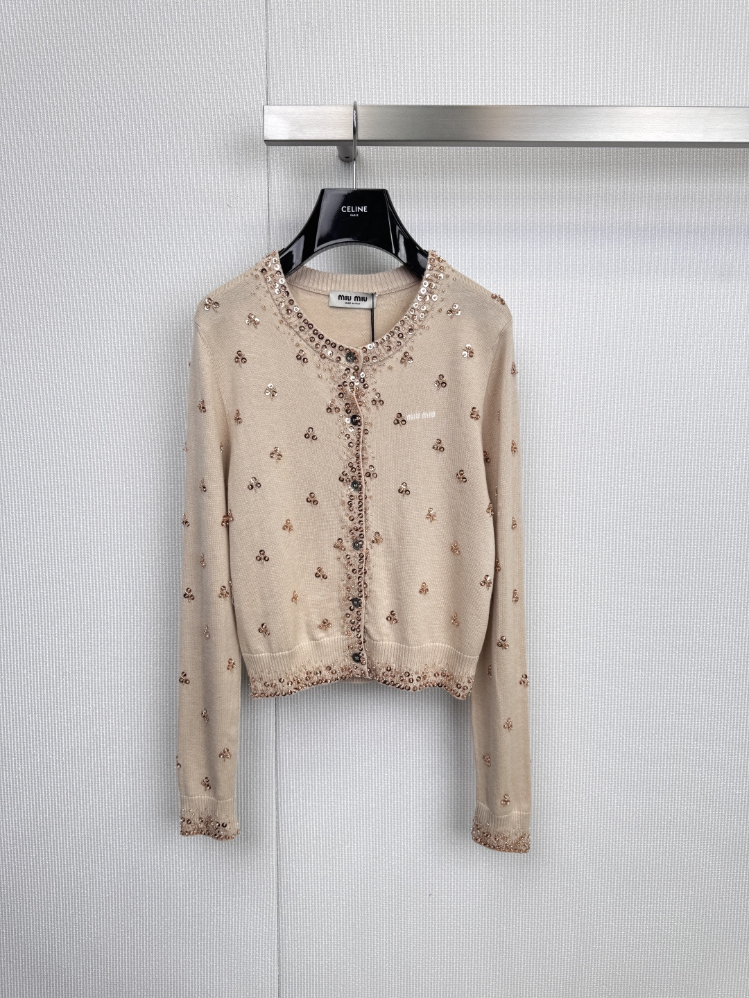 NO:590932,Miu Miu girl's poem sequined knitted cardigan, interpreting Miu  The Miu-style double-sided romantic apricot color is gentle and the olive green is vivid. Between the round neck and the short silhouette, it outlines a just right girly silhouette. The body is decorated with exquisite beaded embroidery - dancing rose gold bows and black four-leaf clover.  Scattered quietly, weaving liveliness and interest into soft needlework, the unique sequin embroidery (the apricot model has a rose gold bow, the green model has a black four-leaf clover pattern) breaks the dullness of the basic knitted style and reflects the delicacy under the light and shadow.  The light shows the brand's iconic playfulness and elegance. The soft apricot color interprets purity and elegance, while the bright olive green brings retro and vitality. The two tones have also become a fashionable tool to lighten up daily looks. The classic round neck design is easy to match; the brand label on the left chest or inside the placket is a low-key proof of extraordinary taste. Whether it is paired with the same series of skirts to create a complete sweet and cool college style, or worn with simple shirts and jeans, it can instantly infuse Miu  Miu's unique 'rebellious girl' soul easily wanders between daytime leisure and evening dating. Size SML,,miumiu,skirts,jeans,shirts,alexander wang19860909Miu Miu少女诗篇珠片针织开衫,诠释Miu Miu式的双面浪漫杏色温柔,橄榄绿鲜活,在圆领与短款廓形间,勾勒出恰到好处的少女感剪影,衣身缀满精致珠片刺绣——玫瑰金色蝴蝶结翩然起舞,黑色四叶草悄然散落,将灵动趣意编织进柔软针线,独具匠心的亮片刺绣（杏色款为玫瑰金色蝴蝶结,绿色款为黑色四叶草图案）,打破基础款针织的沉闷,在光影下折射出细腻光芒,尽显品牌标志性的俏皮与贵气,柔和的杏色色诠释纯净优雅,鲜明的橄榄绿色则带来复古与活力,两种色调,同样成为点亮日常造型的时髦利器,经典的圆领设计,易于搭配；左胸处或衣襟内的品牌标签,低调印证不凡品味,无论是搭配同系列短裙,演绎完整的甜酷学院风,还是内搭简约衬衫、牛仔裤,都能瞬间注入Miu Miu独有的“叛逆少女”灵魂,轻松游走于日间休闲与晚间约会之间.码数SML,,miumiu,skirts,jeans,shirts,alexander wang,Women's clothing