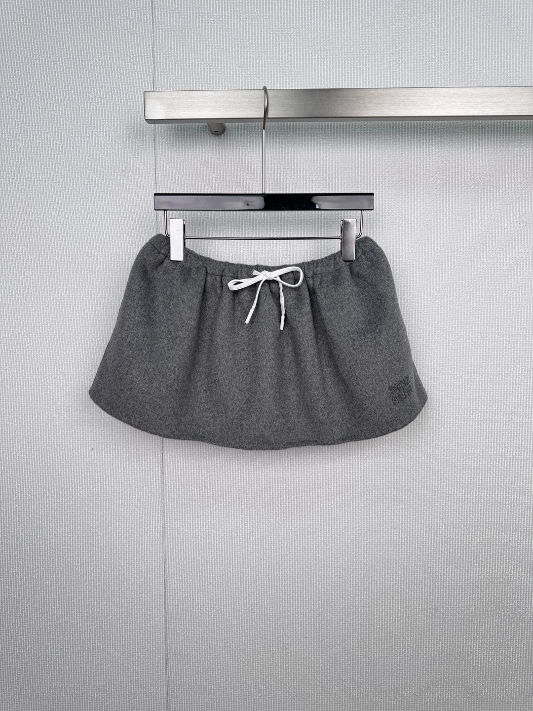 NO:591371,MIU MIU urban roaming sports fashion suit, when sportiness is injected into high fashion, Miu  Miu reshapes the possibilities of daily dressing with its unique 'rebellious girl' language. This set of gray-toned jacket and skirt uses soft gray to interpret the balance of strength and femininity, quietly integrating street vitality into the exquisite silhouette. The short jacket is made of rich wool blend fabric, with a neat straight silhouette to outline a modern figure. The brand logo is embroidered on the left chest to low-key declare one's identity. The zipper pockets on both sides are both practical and decorative, and the cuffs and hem are elastic.  The opening design injects a touch of casual sports vitality into the whole, easily improving the rhythm of the style. The skirt cleverly echoes the overall style, with the iconic sports-style drawstring belt as the core highlight. The white shoelace-style tie runs through the high-waisted skirt, which can not only adjust the tightness at will, but also becomes a visual focus that breaks the rules, injecting a smart and uninhibited personality into the simple gray skirt. The complete dressing philosophy unifies the color and style language, easily creating a complete and advanced total.  look, eliminating the worry of matching, the tough lines of the jacket form a subtle contrast with the soft short silhouette and drawstring details of the skirt, accurately interpreting Miu Miu's core aesthetics, showing an eclectic fashion attitude from urban strolls to casual gatherings. Size SML skirts, miumiu, skirts, jackets & coats, alexander wang19860909MIU MIU 都市漫游运动风尚套装,当运动感注入高级时装,Miu Miu以其独特的“叛逆少女”语言,重塑日常着装的可能.这套灰色调夹克与半裙,以柔和的灰演绎出力量与柔美的平衡,将街头活力悄然融入精致轮廓,短款夹克采用质感丰盈的羊毛混纺面料,以利落的直筒廓形勾勒摩登身形,左胸绣有品牌标识,低调宣示身份.两侧拉链口袋兼具实用性与装饰感,袖口与下摆的弹性收口设计,为整体注入一抹不经意的运动活力,轻松提升造型节奏,半裙巧妙呼应整体风格,以标志性的运动风抽绳腰带为核心亮点.白色鞋带式系绳贯穿高腰裙头,不仅可随心调节松紧,更成为打破常规的视觉焦点,为简约的灰色半裙注入灵动不羁的个性,成套穿搭哲学统一色调与风格语言,轻松塑造完整且高级的total look,省去搭配烦恼,硬朗的夹克线条与半裙的柔美短款廓形、抽绳细节形成微妙对比,精准诠释Miu Miu核心美学,从都市漫步到休闲聚会,皆能展现不拘一格的时髦态度.码数SML 半裙,,miumiu,skirts,jackets & coats,alexander wang,Women's clothing