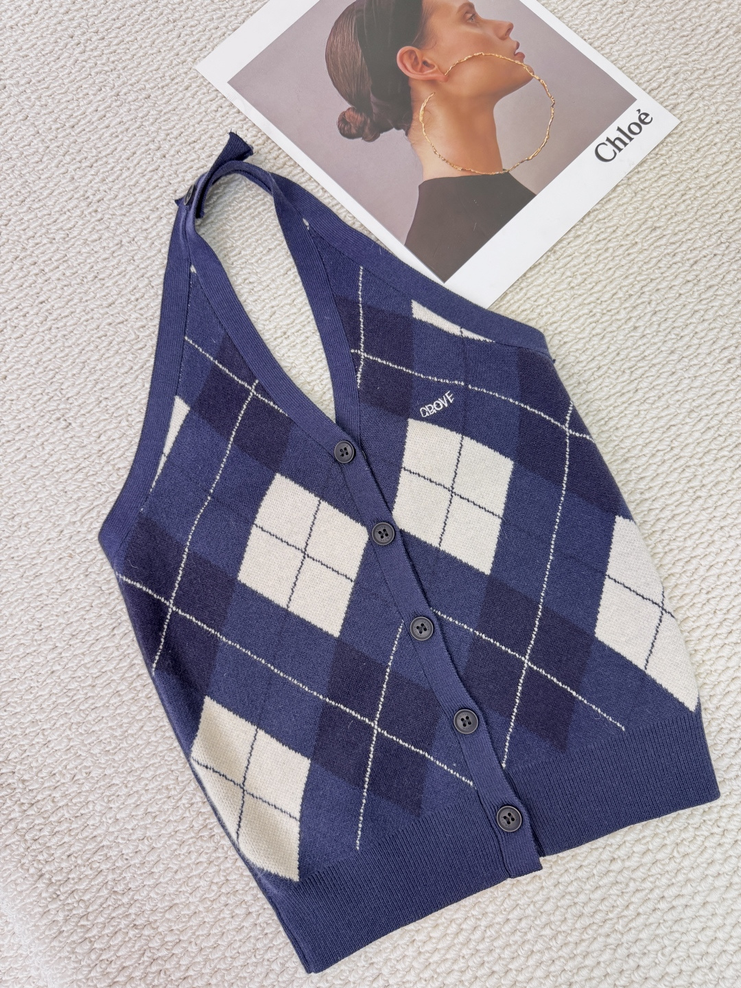 NO:606028,Grove  French elegant halter neck knitted vest unlocks the style of the neck and defines retro modernity. A just right vest is the wisdom of the wardrobe. This halter neck knitted vest uses the classic diamond check pattern as its language. It writes poetry with a unique halter neck design and easily outlines the elegant shoulders and neck.  The lines interpret the effortless sense of luxury, and the unique halter neck design abandons conventional shoulder straps. The unique halter neck cut instantly enhances the fashion, perfectly showing the elegant collarbone and shoulder curves. The button decoration at the back of the neck is not only practical, but also adds a touch of exquisite detail, making you look stylish every time you turn.  The background, dark blue background and refreshing white lines are intertwined, replicating the timeless academic style and retro feelings. The sharp-edged plaid pattern gives the fabric a three-dimensional sense. It is simple and reveals good dressing skills. It can be used as a perfect middle layer in spring and autumn, worn with suits, windbreakers or woolen pants.  Clothing instantly adds layering and fashion to the overall look. It is not just a single item, but also a fashion key that connects retro and modern, casual and formal. The unique neck style becomes the best annotation for your personalized clothing. Code number SML,, business  suit,alexander wang19860909Grove 法式优雅挂脖针织背心,解锁颈间风情,定义复古摩登,一件恰到好处的背心,是衣橱的智慧所在,这款挂脖针织背心,以经典菱形格纹为语言,用别致挂脖设计写诗,轻松勾勒出优雅的肩颈线条,诠释不费力的高级感,别致挂脖设计,摒弃常规肩带,独特的挂脖式剪裁瞬间提升时尚度,完美展现优雅锁骨与肩部曲线.后颈处的纽扣装饰不仅实用,更添一丝精致细节,转身间皆是风景,深蓝底色与清爽白线交织,复刻经久不衰的学院风与复古情怀,棱角分明的格纹图案赋予织物立体感,简约中透露出不俗的穿搭功力,作为春秋季的完美中间层,外搭西装、风衣或毛呢大衣,瞬间增加整体造型的层次感与时尚度,不止是一件单品,更是连接复古与现代、休闲与正式的时尚密钥,让独特的颈间风情,成为你个性衣品的最佳注解.码数SML,,business suit,alexander wang,Women's clothing