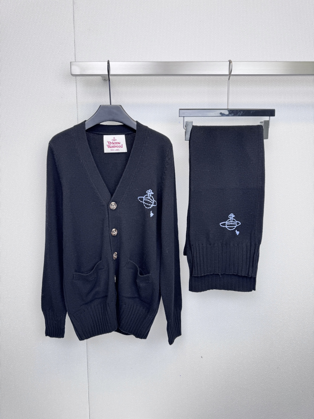 NO:607761,Vivienne Westwood  Classic Saturn logo knitted two-piece set, using textured thick knitting to interpret uninhibited British elegance. The deep V-neck cardigan is embellished with four retro buttons. Paired with the elegant scarf of the same series, this set unlocks the perfect look of the 'Western Queen Mother', whether it is layered or casually draped.  Both are irreplaceable style statements. The suit includes a scarf made of the same material, with Saturn patterns on both ends. It perfectly echoes the cardigan and can be easily paired with a sense of layering and luxury. It is a timeless fashion investment in the wardrobe. Size SML, alexander  wang19860909Vivienne Westwood 经典土星标志针织两件套,以质感粗针针织演绎不羁的英伦优雅,深V领开衫,四个复古纽扣点缀,搭配同系列飘逸围巾,一套解锁「西太后」的满分造型,无论是层叠穿搭还是随性披挂,皆是无法复刻的风格宣言,套装内含同款材质围巾,两端均饰有土星图案,与开衫完美呼应,轻松搭配出层次感与高级感,是衣橱里永不过时的时尚投资.码数SML,,alexander wang,Women's clothing