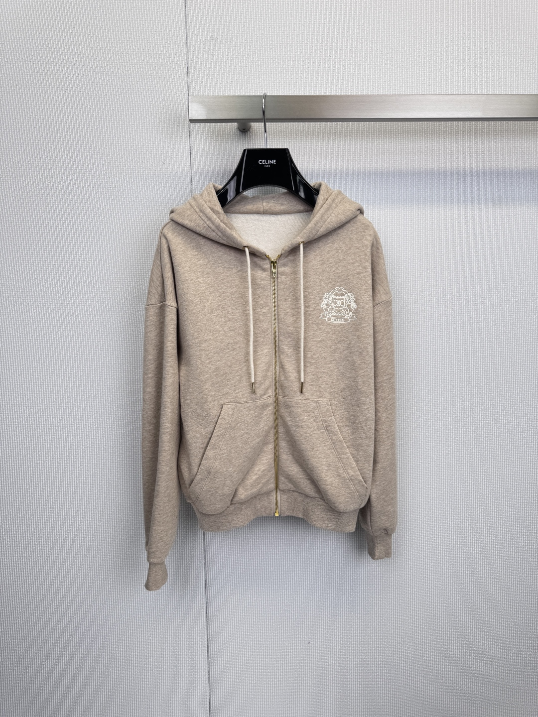 NO:621545,CELINE zippered hooded sweatshirt, a mobile comfort barrier, and exquisite relaxation philosophy. When French elegance meets street comfort, this zippered hooded sweatshirt was born. It uses calm light gray as the base tone, and integrates effortless high-end sense into daily life through neat tailoring and iconic details. Iconic details,  Outlining a delicate silhouette, the classic Arc de Triomphe tower and monogram on the chest are exquisitely presented with pure white lines, becoming the visual focus in simplicity. The unique golden front zipper is not only easy to put on and take off, but its metallic luster adds a touch of casual luxury to the low-key gray. The symmetrical pockets on both sides combine practicality and smooth styling.  Balanced feel, comfortable touch, defining relaxed aesthetics, selected high-quality cotton fabrics, providing a cloud-soft skin-friendly experience. The hooded design and white drawstring retain the casual gene of sports items, while the three-dimensional tailoring that fits well but is not tight ensures comfort and propriety when wearing, whether it is paired with jeans for casual wear  Style, or layered under a suit jacket, this sweatshirt can easily become a core item in the wardrobe, perfectly blending urban modernity and street relaxation. Size SML, celine, hoodie, sweatshirts, jeans, jackets  & coats,business suit,hats,alexander wang19860909CELINE拉链连帽卫衣,移动的舒适壁垒,精致的松弛哲学,当法式优雅遇见街头舒适,便诞生了这款拉链连帽卫衣,它以沉静浅灰为基调,通过利落剪裁与标志性细节,将毫不费力的高级感融入日常,标志性细节,勾勒精致轮廓,胸前经典的凯旋门铁塔与字母组合以纯白线条精致呈现,成为简约中的视觉焦点,独特的金色前拉链不仅便于穿脱,其金属光泽更在低调灰色上增添一抹不经意的奢华.两侧对称口袋兼顾实用性与造型的平衡感,舒适触感,定义松弛美学,精选优质棉质面料,提供云朵般柔软的亲肤体验,连帽设计与白色抽绳保留了运动单品的休闲基因,而合身却不紧绷的立体剪裁,确保了穿着时的自在与得体,无论是搭配牛仔裤演绎休闲风尚,或是在西装外套下作为层次内搭,这件卫衣都能轻松成为衣橱中的核心单品,将都会摩登与街头松弛完美融合.码数SML,,celine,hoodie,sweatshirts,jeans,jackets & coats,business suit,hats,alexander wang,Women's clothing