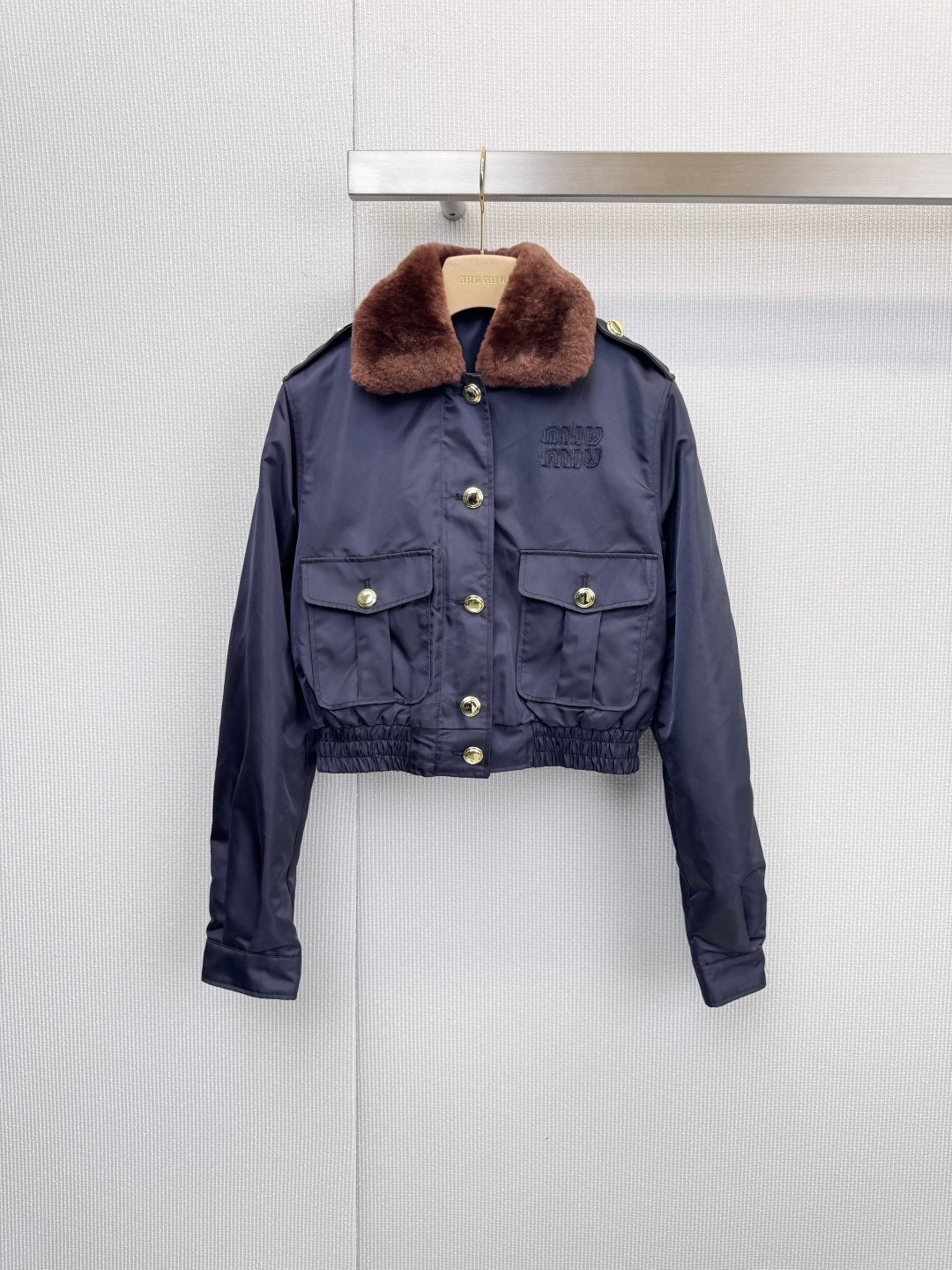 NO:623868,MiuMiu workwear-style short suits are straightforward and elegant, defining contemporary fashion. This series of suits combines pragmatic workwear genes with Miu  Miu's unique delicate girlishness is cleverly integrated to create a fashionable style that is both capable and energetic. The dark blue tone is calm and versatile, and the crisp and stylish tailoring shows a sense of strength. A circle of brown shearling around the collar is not only soft to the touch, but also injects a touch of luxury and warmth into the overall shape. The front of the jacket and the flap pockets are dotted with multiple metal buttons, which are both functional and decorative. The clear 'MIU' is embroidered on the chest.  MIU' brand logo, elastic design on the cuffs and hem, neat and windproof. The main body is made of recycled nylon, which reflects the brand's commitment to sustainable fashion. The lining is viscose fiber, which is comfortable and skin-friendly. The filler is 55 recycled polyester fiber and 45 polyester fiber, which is light and warm. Size SML,,miumiu,jackets & coats,alexander wang19860909MiuMiu工装风短款套装,率性优雅,定义当代时尚,本系列套装将实用主义的工装基因与Miu Miu独有的精致少女感巧妙融合,打造出既干练又充满活力的时尚造型,深蓝色调沉稳百搭,挺括有型的剪裁彰显力量感,领口处环绕的一圈棕色羊毛皮,不仅触感柔软,更为整体造型注入一抹奢华温暖的气息,夹克正面与带盖口袋上点缀着多颗金属纽扣,兼具功能性与装饰性,胸前绣有清晰的“MIU MIU”品牌标识,袖口与下摆的松紧设计,利落且防风,主体采用再生锦纶制成,体现了品牌对可持续时尚的承诺,衬里为粘胶纤维,穿着舒适亲肤.填充物为55再生聚酯纤维与45聚酯纤维,轻盈保暖. 码数SML,,miumiu,jackets & coats,alexander wang,Women's clothing