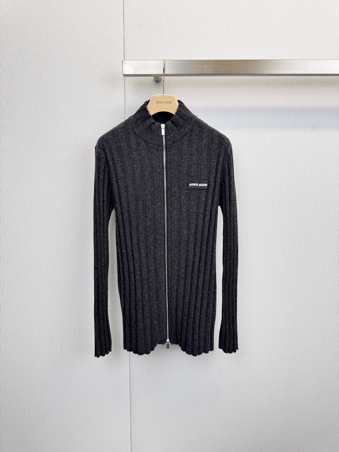 NO:625553,MiuMiu dark gray ribbed knitted cardigan, Italian sweet and cool, defines a lazy and high-end feel. The minimalist dark gray tone collides with the three-dimensional rib texture, using refined lines to outline an effortless high-end feel. The iconic stand-up collar is paired with a smooth metal zipper, which is both handsome and elegant. The exquisite brand logo on the left chest is low-key.  To show your identity, the high-quality wool material is selected to bring a soft, skin-friendly, warm and breathable close-fitting touch, creating a cloud-like wrapping experience. Wear it with a basic white T and straight trousers to easily create a capable and intellectual workplace image. Pair it with a dress or denim items to instantly unlock a relaxed atmosphere that coexists with laziness and sophistication.  Code numberSML,,miumiu,skirts,alexander wang19860909MiuMiu深灰罗纹针织开衫,意式甜酷,定义慵懒高级感,极简深灰调性与立体罗纹肌理碰撞,以精炼线条勾勒出毫不费力的高级感,标志性立领搭配顺滑金属拉链,兼具帅气与优雅,左胸精致品牌标识低调彰显身份,甄选优质羊毛材质,带来柔软亲肤、温暖透气的贴身触感,打造云朵般包裹体验,内搭基础白T与直筒西裤,轻松营造干练知性的职场形象,搭配连衣裙或牛仔单品,瞬间解锁慵懒与精致并存的松弛氛围. 码数SML,,miumiu,skirts,alexander wang,Women's clothing