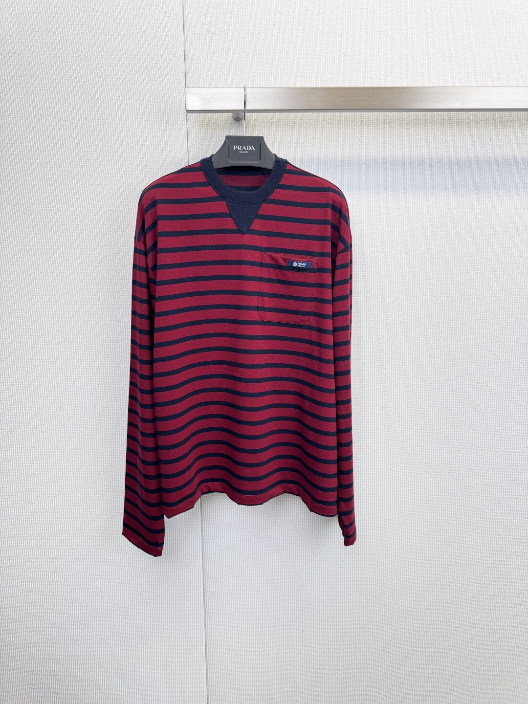 NO:626619,Prada Prada burgundy classic striped long-sleeved T-shirt, unlocking Prada’s sense of relaxation!  This striped shirt is the 'advanced answer' for early autumn. Who says luxury has to be tight?  This red and black striped long-sleeved T-shirt is the best interpretation of 'relaxation and moderation'. It is made of pure cotton fabric, which wraps the comfort of autumn with a soft touch. It is skin-friendly and breathable, giving the body full freedom. The iconic red and black color scheme is eye-catching but not overly ostentatious, instantly brightening the overall look. It looks more retro and modern in front of the light green background. The exquisite small logo on the left chest quietly tells a story  The brand's identity is low-key elegance that is instantly recognizable, with a well-fitted yet unrestricted silhouette that perfectly outlines the body shape. It can be worn alone or as an inner layer with a sense of layering. Paired with a pair of cool sunglasses and dark bottoms, you can easily create a casual yet high-end street style. Whether it is a weekend outing or daily commuting, it is an indispensable 'universal item' in your wardrobe.  Size SML,,prada,prada,tees,t-shirt,alexander wang19860909Prada普拉达酒红色经典条纹长袖T恤,解锁Prada的松弛感！这件条纹衫是早秋的「高级答案」,谁说奢华一定要紧绷？这件红黑条纹长袖T恤,正是「松弛有度」的最佳诠释,甄选纯棉面料,以柔软触感包裹秋日惬意,亲肤透气,给予身体充分的自由,标志性的红黑配色,醒目却不过分张扬,瞬间提亮整体造型,在浅绿背景前更显复古摩登,左胸处的精致小标识,悄然诉说着品牌身份,是懂得人一眼便知的低调优雅,合身却不拘束的版型,完美勾勒身形,单穿或作为内搭都极具层次感,搭配一副酷感墨镜与深色下装,便能轻松营造出随性又高级的街头风格,无论是周末出游还是日常通勤,它都是你衣橱里不可或缺的“万能单品”. 码数SML,,prada,prada,tees，t-shirt,alexander wang,Women's clothing