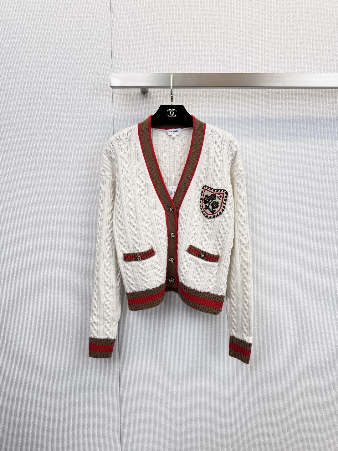 NO:626653,Chanel college-style V-neck knitted cardigan is made of textured white cable knitting to outline the warm silhouette of autumn. Brown and red stripes are used along the V-neck, cuffs and pocket edges to outline clear layers, instantly stimulating the vision. The exclusive flower badge above the left pocket is like an elegant mark, telling the brand's genes in every detail. It is made of pure cashmere and wrapped with a soft touch.  It wraps up the body and mind, whether it is paired with a dress to interpret French romance, or paired with jeans to show a casual attitude, it is a tasteful choice. This version focuses on the core selling point of 'cashmere', emphasizing its scarcity and skin-friendly experience, creating a low-key and luxurious wearing feeling, and the tenderness of being kissed by a cloud. The luxury of this cardigan comes from the first softness when the fingertips touch it. On the label, '  'Cachemire' is its quality medal. It selects high-quality cashmere to give the skin a skin-to-skin experience of being as light as a cloud and wrapping warmth. The classic cable texture and brand emblem are embellished, giving this warmth without losing the exquisite style. It is not only a cardigan, but also a close-fitting comfort comfort, suitable for you who pursue inner quality. Size SML, chanel, skirts, jeans, alexander wang19860909Chanel学院风V领针织开衫,以质感白色绞花针织,勾勒秋日温润轮廓,V领沿线、袖口与口袋边缘,以棕红条纹勾勒出清晰层次,瞬间跃动视觉,左侧口袋上方的专属花朵徽章,宛如一枚优雅印记,于细节处诉说品牌基因,纯羊绒材质,以柔软触感包裹身心,无论是搭配连衣裙诠释法式浪漫,还是搭配牛仔裤彰显随性态度,皆是品味之选,此版本主打“羊绒”这一核心卖点,强调其稀缺性与亲肤体验,塑造低调奢华的穿着感,被云朵亲吻的温柔,这件开衫的奢侈,源于指尖触碰时的第一缕柔软.标签上「 Cachemire」是它的品质勋章,甄选优质山羊绒,赋予肌肤云朵般轻盈、包裹暖意的亲肤体验,经典绞花纹理与品牌徽章点缀其间,让这份温暖不失精致格调.它不仅是件开衫,更是贴身的舒适慰藉,适合追求内在品质的您.码数SML,,chanel,skirts,jeans,alexander wang,Women's clothing