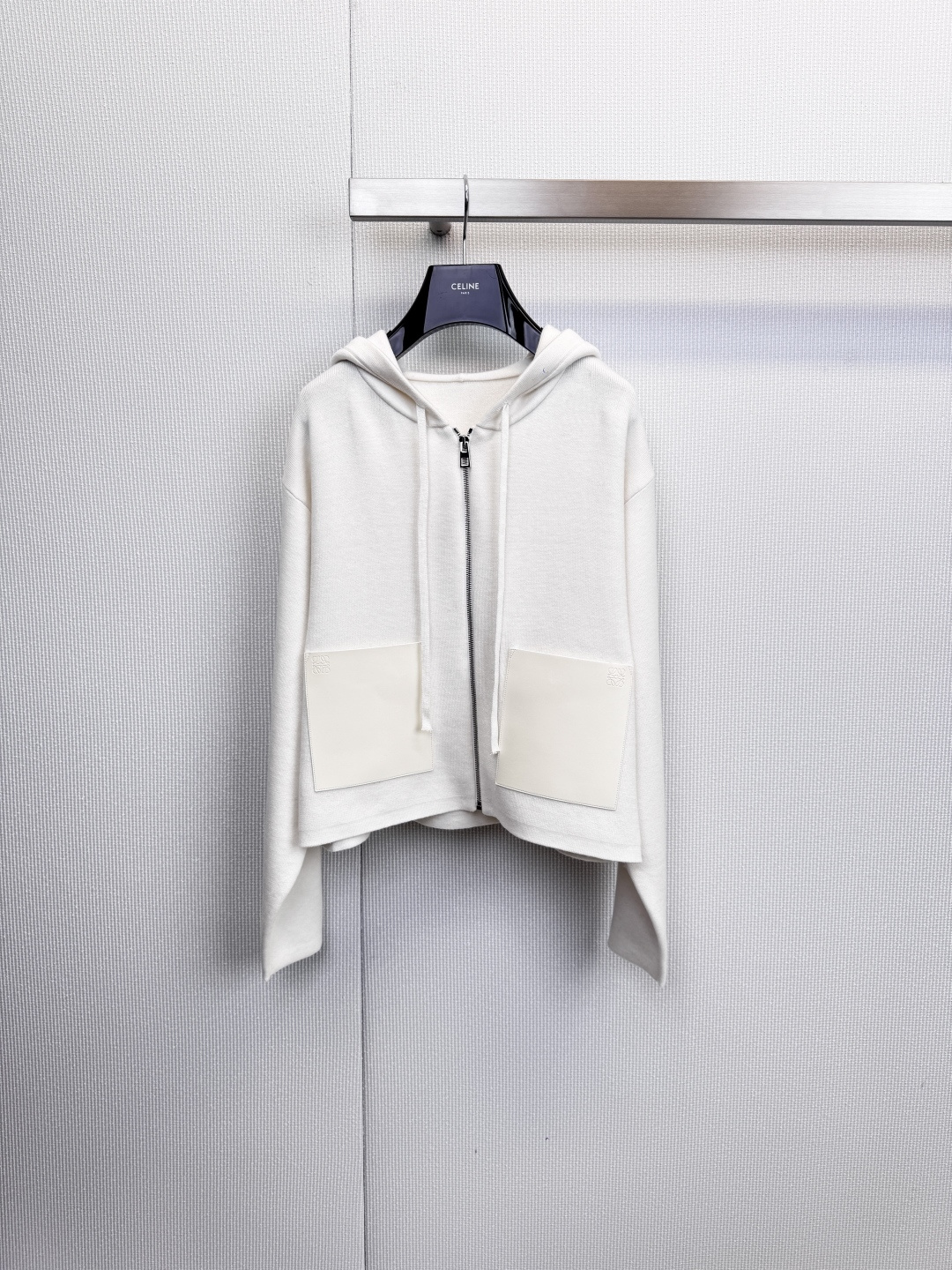 NO:628960,LOEWE  Hooded knitted zipper cardigan, urban roaming, and interpretation of relaxed aesthetics. This hooded knitted cardigan redefines modern casual style with refined tailoring and exquisite details. The classic hooded design and front zipper give the wearer a casual and comfortable experience. The hem is cleverly designed with asymmetrical design to create a comfortable look.  It breaks the rules and reveals a casual design sense in the dynamic. The high-quality leather patch pockets on both sides are not only practical, but also become the finishing touch, quietly improving the overall texture. The fabrics are strictly selected from 95% wool blended material, 4% nylon, 1% spandex, ensuring that the clothing has the natural warmth and soft touch of wool.  , while the blended material enhances elasticity and durability, making it comfortable and unrestricted to wear. Available in classic black and white and elegant off-white colors, it can be easily integrated into your daily wardrobe. Whether worn with a simple T-shirt and jeans to create a relaxed street look, or layered under a coat to inject a sense of relaxation into your commuting look.  It integrates LOEWE's insistence on craftsmanship into daily wear. It is a must-have item that combines comfort, texture and design. Size SML, loewe, jeans, tees, t-shirt, hats, alexander  wang19860909LOEWE 连帽针织拉链开衫,都市漫游,演绎松弛美学,这款连帽针织开衫,以精炼的剪裁与考究的细节,重新定义现代休闲风格,经典连帽设计与前襟拉链,赋予穿着者随性自在的体验.下摆巧妙采用不对称设计,打破常规,于动态间流露不经意的设计感,两侧的优质皮质贴袋,不仅实用,更成为点睛之笔,悄然提升整体质感,严格甄选面料用95羊毛混纺材质,4锦纶,1氨纶,确保衣物拥有羊毛的天然保暖性与柔软触感,同时混纺材质增强了弹力与耐用度,穿着舒适无拘束,提供经典黑白及雅致米白等配色,轻松融入日常衣橱.无论是内搭简约T恤与牛仔裤,营造轻松出街造型,还是层搭于大衣之内,为通勤装扮注入一份松弛感,皆能游刃有余,它将LOEWE对工艺的坚持融入日常穿着,是兼具舒适、质感与设计感的必备单品.码数SML,,loewe,jeans,tees，t-shirt,hats,alexander wang,Women's clothing