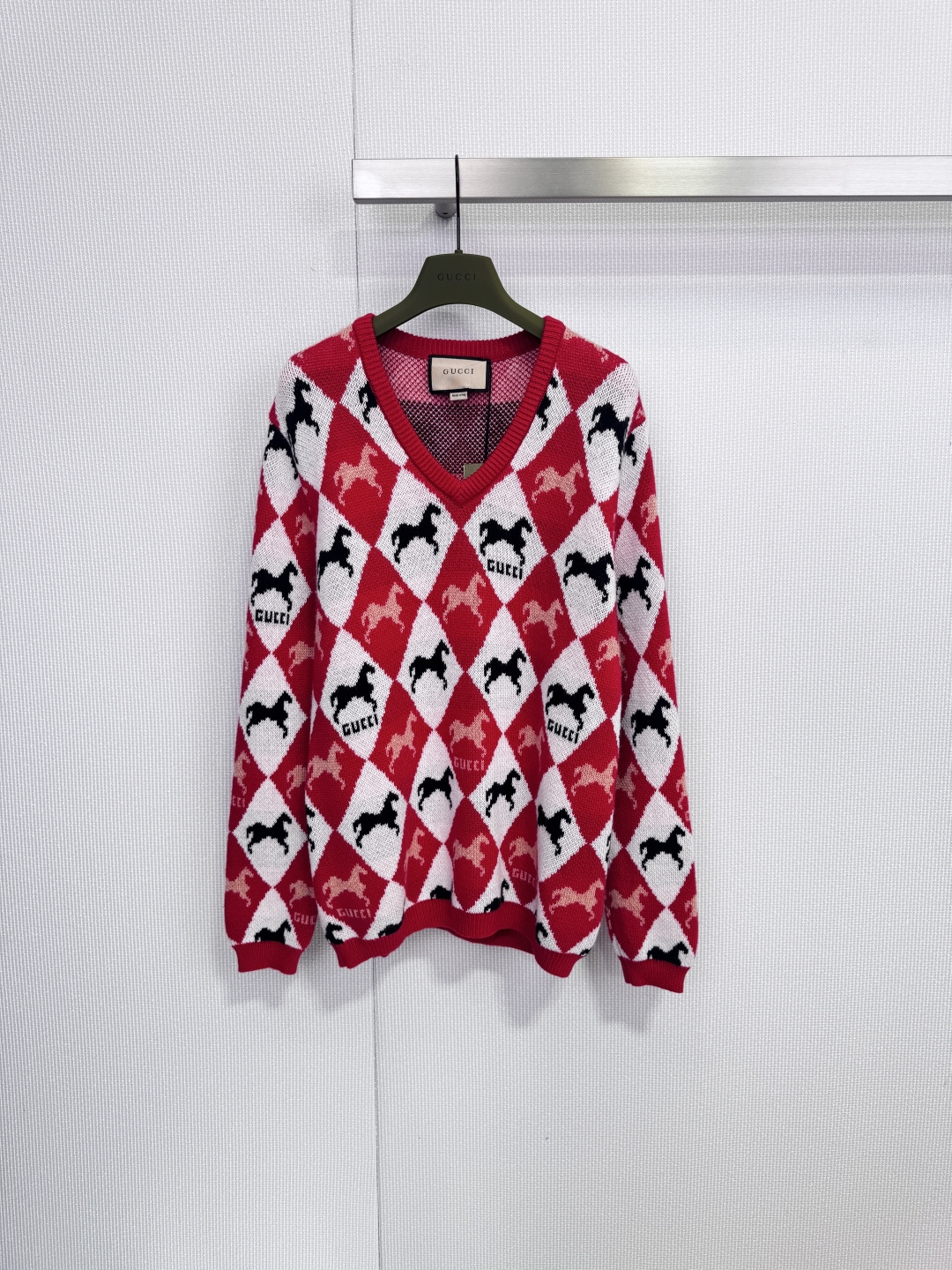 NO:652581,Gucci pony jacquard  The V-neck sweater uses the classic red, white, and black rhombus plaid to create a highly recognizable visual style. Each rhombus unit is decorated with an exquisite black horse silhouette and repeated 'GUCCI' brand logo, and every detail is revealed.  Showing the brand's genes, the red and white rhombus plaid contrasts sharply, and is matched with brand element patterns, which is retro and fashionable. It adopts a V-neck design, which can well modify the neck line. The cuffs and hem are ribbed to ensure that the shape is stiff and not easy to deform, and the fabric is beautiful.  The delicate knitted texture is visually soft and elastic. The fabric composition is a golden ratio of 70% wool and 30% cashmere. It not only ensures the structure of the clothing, but also incorporates the ultimate softness and warmth of cashmere. It is suitable for autumn and winter wear. It can be worn with basic items to create a daily casual retro look, or it can be used in slightly more formal occasions to inject a touch of effortless fashion and luxury into the overall look. Size SML, gucci, gold, alexander  wang19860909Gucci小马提花 V领针织衫,以经典的红、白、黑三色菱形格纹,构建出极具辨识度的视觉风格.每个菱形单元内,均饰有精致的黑色马匹剪影与重复的“GUCCI”品牌标识,细节中尽显品牌基因,红白菱形格纹对比鲜明,搭配品牌元素图案,复古而时髦,采用V领设计,能很好地修饰颈部线条,袖口与下摆采用罗纹收边,确保版型挺括不易变形,面料呈现细腻的针织肌理,视觉上柔软且富有弹性,面料成分为70羊毛与30羊绒的黄金配比,在保证衣物结构的同时,融入了羊绒的极致柔软与保暖性,适合秋冬季节穿着,既可内搭基础款打造日常休闲的复古Look,也能在稍正式的场合中,为整体造型注入一丝毫不费力的时髦与奢华感.码数SML,,gucci,gold,alexander wang,Women's clothing