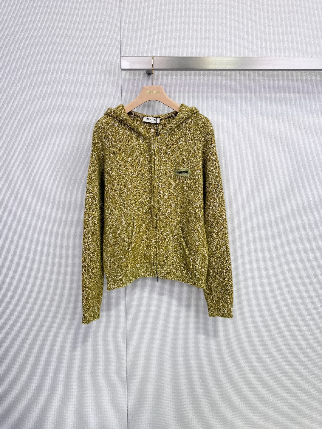 NO:652589,Miu Miu hooded knitted cardigan, combining retro college style and sweet coolness, this Miu  The Miu hooded knitted cardigan uses classic thick knit texture and neat tailoring to create a lazy and refined daily look. It is not only a warm companion to resist the slight cold, but also a fashion statement that highlights your unique personality. It adopts a loose and comfortable hooded style, taking into account casual sexiness and tolerance. It is easy to match and has a busty look.  There is a classic green cotton brand logo on the front, which highlights the brand's charm in a low-key manner. The practical front pocket design provides warmth and a place for your hands. It is available in two iconic colors of yellow-green mixed yarn and beetroot powder. The yellow-green color is rich in layering and vitality, while the pink version is gentle and eye-catching, both of which perfectly interpret Miu  Miu's unique aesthetics. The main body is made of wool, which brings soft skin-friendly touch and excellent warmth. The tweed-like weaving texture adds rich texture. With its outstanding texture, comfort and design, this cardigan can easily brighten up daily wear. It is the finishing touch to create a fashionable casual or retro literary style. Size SML,, miumiu, hats, alexander wang19860909Miu Miu 连帽针织开衫,融合复古学院风与甜美酷感,这款Miu Miu连帽针织开衫以经典的粗棒针纹理与利落剪裁,打造出慵懒而精致的日常造型,它不仅是抵御微寒的温暖伴侣,更是彰显独特个性的时尚宣言,采用宽松舒适的连帽款式,兼顾随性感与包容度,易于搭配,胸前饰有经典的绿色棉质品牌标识,低调彰显品牌魅力.实用的前插袋设计,为双手提供暖意与安放之处,提供黄绿混纱与甜菜根粉两款标志性色调.黄绿色调富有层次与生机,粉色款则温柔亮眼,均完美诠释Miu Miu的独特美学,主体采用羊毛制成,带来柔软亲肤的触感与出色的保暖性,粗花呢般的编织纹理更增添了丰富的质感,这款开衫以其出众的质感、舒适度与设计感,轻松点亮日常穿搭,是打造时髦休闲或复古文艺风格的点睛之选. 码数SML,,miumiu,hats,alexander wang,Women's clothing