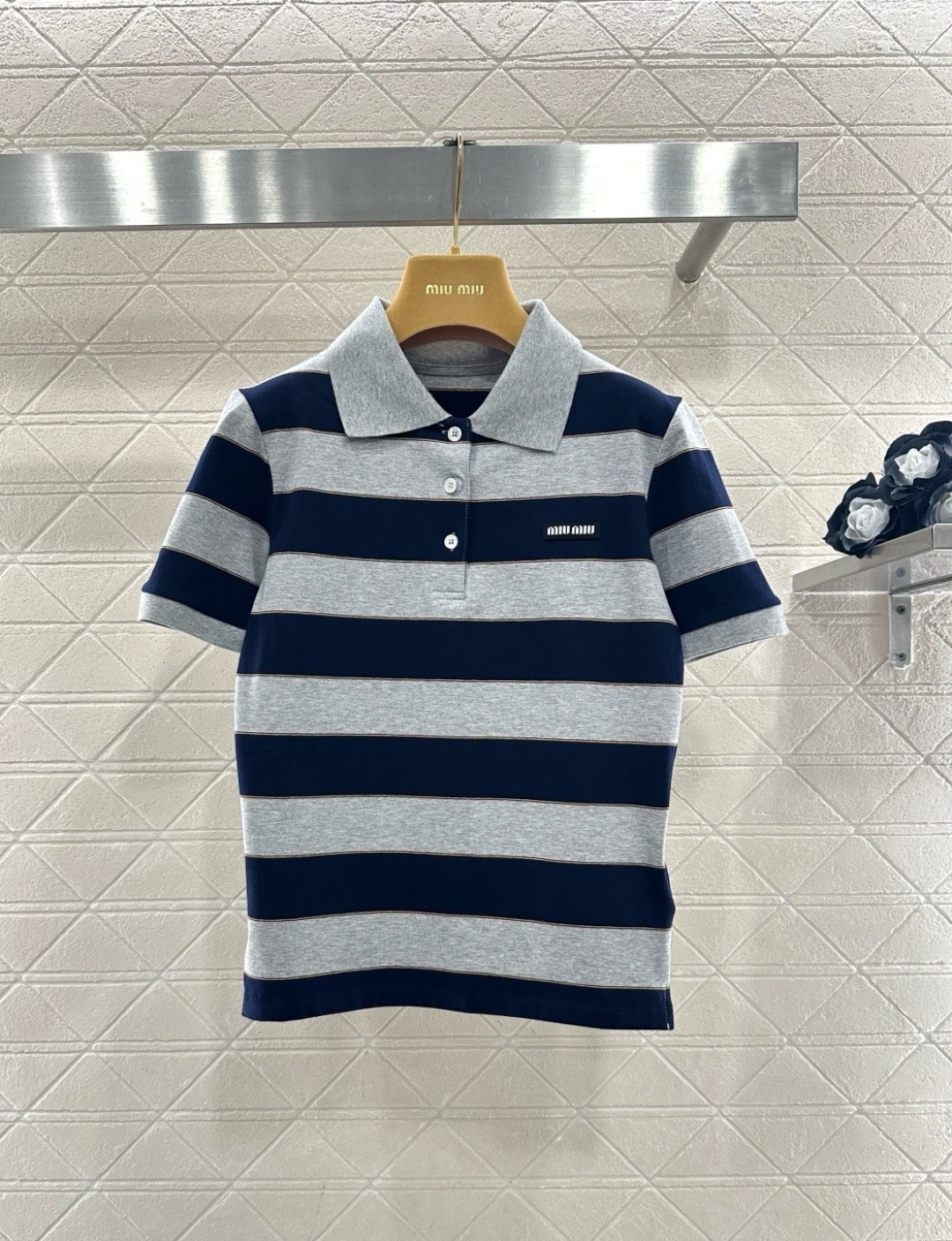 NO:709052,MiuMiu26 early spring series blue and gray striped Polo shirt, cotton material, soft and breathable, super comfortable to wear in spring and summer, navy blue + light hemp gray wide stripes, thin gold thread outline, full of retro girly feel, classic lapel + three buttons, small logo on the chest is very recognizable, college style design, looks great with pleated skirts or casual shorts, can be easily used for commuting, campus, and weekend outings, fashionable and practical!  Code numberSML,,miumiu,skirts,shorts,19860909MiuMiu26早春系列蓝灰条纹Polo衫,棉材质,柔软透气,春夏穿超舒服,藏蓝+浅麻灰宽条纹,细金线勾勒,复古少女感满满,经典翻领+三颗纽扣,胸前小Logo超有辨识度,学院风设计,搭百褶裙或休闲短裤都很出彩,通勤、校园、周末出街都能轻松驾驭,时髦又实用！ 码数SML,,miumiu,skirts,shorts,,Women's clothing