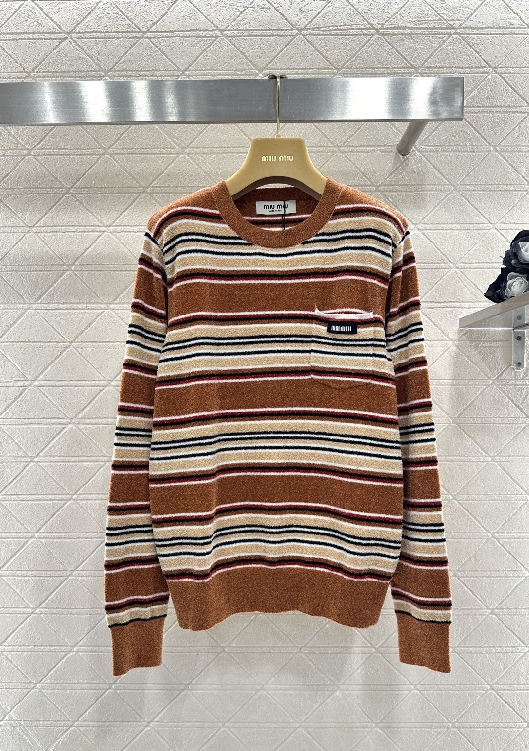 NO:710101,MiuMiu 2026 spring and summer series striped knitted sweater, mainly brown, with off-white, dark red and black pinstripes, full of retro college style, soft knitted fabric, comfortable and warm, small chest pocket + brand embroidery, full of details, loose version, easy to create a lazy and casual outfit, it looks great whether paired with jeans or a pleated skirt, it can be easily managed for daily leisure or light commuting, fashionable and practical!  Code numberSML,,miumiu,skirts,jeans,sweaters,19860909MiuMiu 2026春夏系列条纹针织毛衣,棕色为主,搭配米白、深红、黑色细条纹,复古学院风满满,柔软针织面料,舒适又保暖,胸前小口袋+品牌刺绣,细节感十足,宽松版型,轻松打造慵懒随性穿搭,无论配牛仔裤还是百褶裙都很出彩,日常休闲或轻通勤都能轻松驾驭,时髦又实用！码数SML,,miumiu,skirts,jeans,sweaters,,Women's clothing