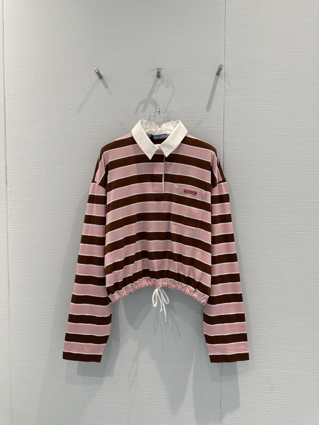 NO:713573,Prada 2026 early spring series pink and brown striped drawstring Polo shirt, double-strand mercerized cotton, soft and breathable, pink and brown stripes + white lapels, full of college style, adjustable hem drawstring, easy to switch between casual or sweet and cool styles, the small red label on the chest is very recognizable, it goes well with pleated skirts or jeans, it can be easily controlled when going out, commuting, and traveling in early spring, fashionable and practical!  Code numberSML,,prada,skirts,jeans,19860909Prada 2026早春系列粉棕条纹抽绳Polo衫,棉支双股丝光工艺,柔软亲肤又透气,粉棕条纹+白色翻领,学院风满满,下摆抽绳可调节版型,轻松切换休闲or甜酷风格,胸前红色小标超有辨识度,搭配百褶裙或牛仔裤都很出彩,早春出街、通勤、旅行都能轻松驾驭,时髦又实用！码数SML,,prada,skirts,jeans,,Women's clothing