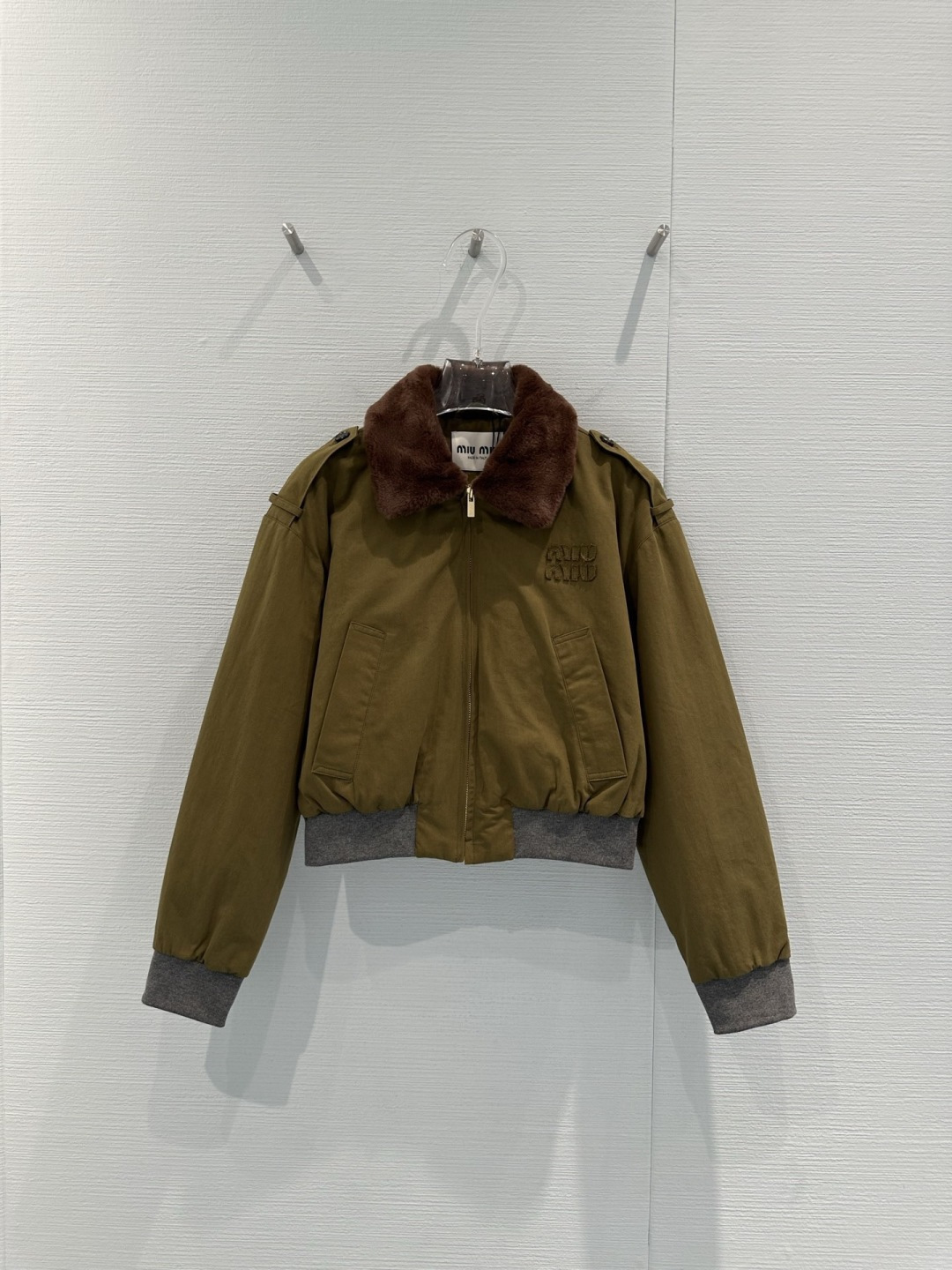 NO:716077,MiuMiu 2026 early spring series military green short jacket, cotton fabric + brown plush lapel, full of retro college style, embossed logo on the chest is very recognizable, ribbed cuffs and hem improve comfort, short design is neat, looks great with high-waisted skirt or jeans, easy to switch between sweet and cool or retro style, can be easily used for daily commuting and casual occasions, it is a must-have highlight item for early spring!  Size SML,,miumiu,skirts,jeans,jackets & coats,19860909MiuMiu 2026早春系列军绿色短款夹克,棉质面料+棕色毛绒翻领,复古学院风满满,胸前浮雕徽标超有辨识度,罗纹袖口和下摆提升舒适度,短款设计利落,搭配高腰裙or牛仔裤都很出彩,轻松切换甜酷or复古风,日常通勤、休闲场合都能轻松驾驭,是早春穿搭必备亮点单品！码数SML,,miumiu,skirts,jeans,jackets & coats,,Women's clothing