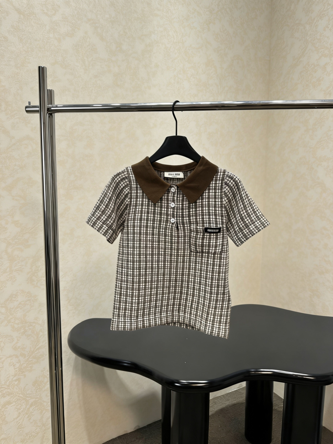 NO:793429,MiuMiu 2026 new spring and summer plaid knitted short-sleeved POLO shirt. This POLO shirt is designed with brown and white plaid, with dark brown lapels. It is retro and casual. The cotton fabric is breathable and comfortable. It is very suitable for summer. It has short sleeves + three buttons and small pockets on the chest. It is practical and detailed. It can be easily used for daily commuting and leisure occasions. It goes well with jeans or casual pants. A must-buy for simple style lovers!  Size SML,,miumiu,jeans,T-shirt,19860909MiuMiu2026春夏新款格纹针织短袖POLO衫,这款POLO衫采用棕白格纹设计,搭配深棕翻领,复古又休闲,棉质面料透气舒适,夏天穿超合适,短袖+三颗纽扣,胸前小口袋点缀,实用又有细节感,日常通勤、休闲场合都能轻松驾驭,搭配牛仔裤或休闲裤都很OK,简约风格爱好者必入！码数SML,,miumiu,jeans,T-shirt,,Women's clothing