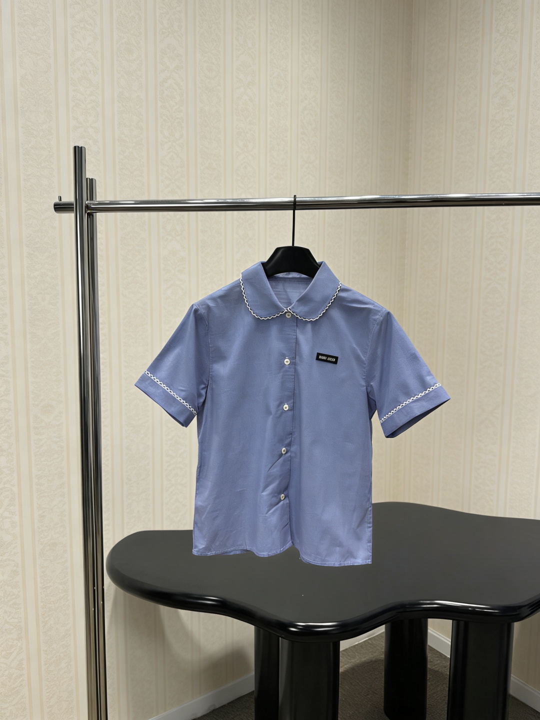 NO:793904,MiuMiu 2026 spring and summer blue college style shirt, light blue cotton poplin, soft and comfortable, white embroidered lace embellishes the collar and cuffs, perfect details, black 'Miu Miu' logo on the chest, full of brand sense, slim straight version, short-sleeved design, very suitable for spring and summer, paired with the same series of plaid skirts, youthful and age-reducing, full of girlishness, easy to control for commuting, dating, and daily life, sweet and advanced, a must-have for college style lovers!  Size SML,,miumiu,skirts,shirts,T-shirt,19860909MiuMiu2026春夏蓝色学院风衬衫,浅蓝棉质府绸,柔软舒适,白色刺绣花边点缀领口和袖口,细节满分,胸前黑色“Miu Miu”标志,品牌感十足,修身直筒版型,短袖设计,春夏穿超合适,搭配同系列格纹半裙,青春减龄,少女感爆棚,通勤、约会、日常都能轻松驾驭,甜美又高级,学院风爱好者必入！码数SML,,miumiu,skirts,shirts,T-shirt,,Women's clothing