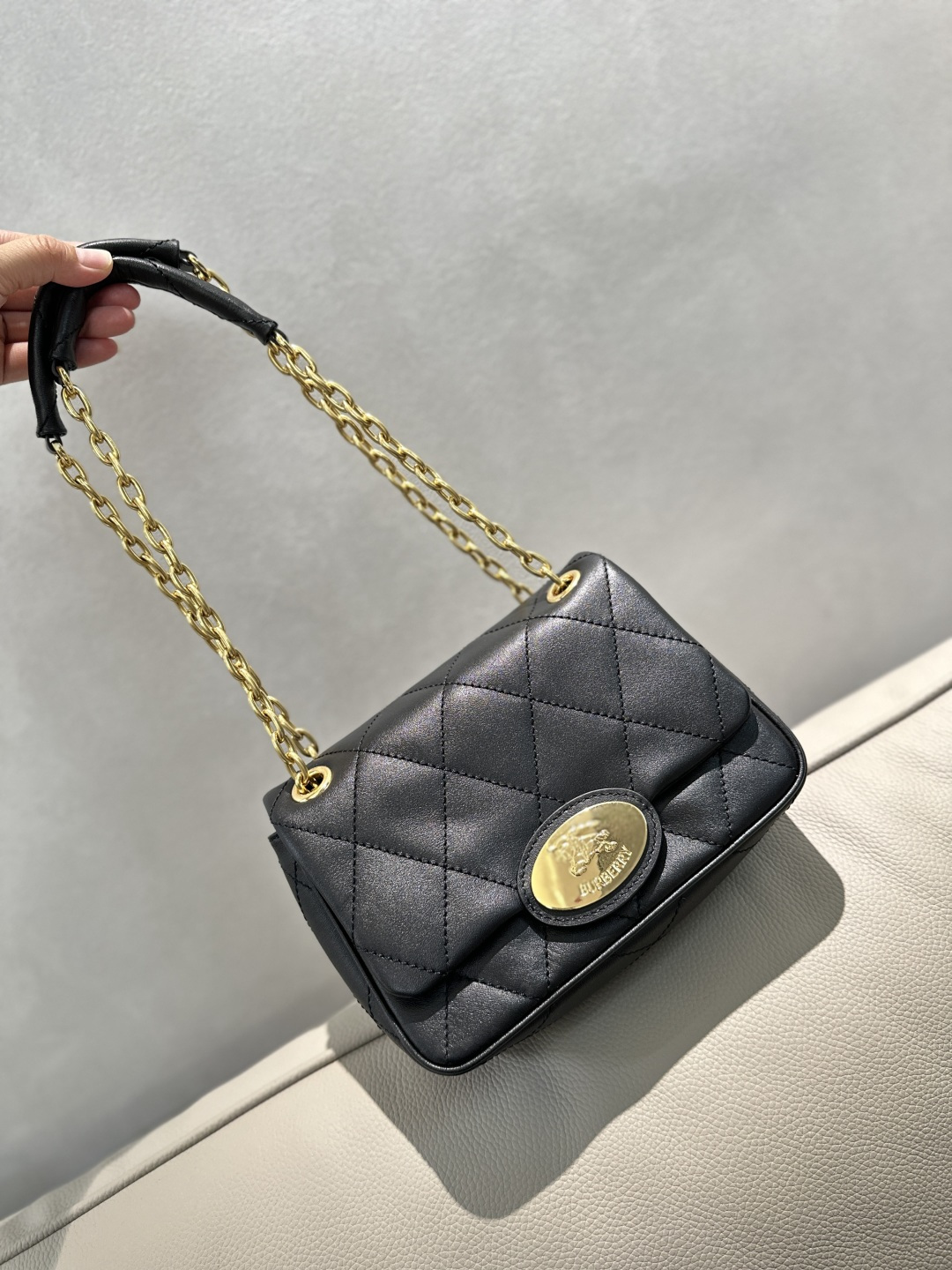 B brand's latest handbag features a stitched small cowhide leather fabric, crafted with a unique technique to give it a soft and flexible textured surface. The delicate bag design is adorned with a metal knight emblem, inspired by the archival patterns of the brand's bags from the 1980s. It comes with a lightweight chain strap with leather accents, allowing for versatile styling as a crossbody or shoulder bag. The leather and chain shoulder strap is embellished with engraved equestrian knight emblem (EKD) on the metal hardware. Dimensions: 20.5 x 7.5 x 16cm. Model number: 264175. image 1