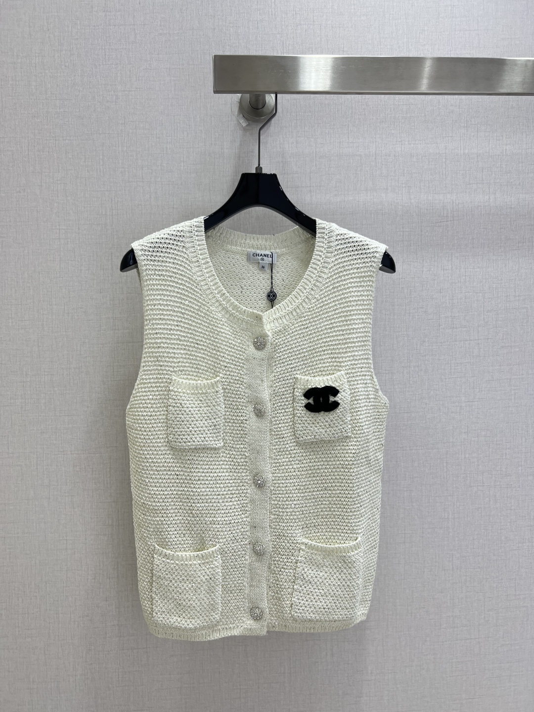 NO:901091,Highly recommended for 26 spring and summer new style. Pocket double C knitted sleeveless top. White hollow knitted small fragrant vest. Delicate and breathable hollow texture with fine starlight sparkles. It shines in the sun. Refreshing and transparent. It is not boring to wear alone in spring and summer. Classic round neck does not pick up the neck line. Exquisite diamond-encrusted buttons in the front row. The opening and closing texture is full. Four pockets are practical and retro. The black double C logo on the left pocket highlights the brand heritage in a low-key manner. Black and white contrasting colors are simple and advanced.  The sleeveless version is neat and slimming. The loose cut accommodates all body shapes. The light and luxurious texture can be easily worn to give you the aura of a high-end celebrity. One color. SML code. High quality.19860909强烈推荐 26春夏新款 口袋双C针织无袖上衣 白色镂空针织小香风马甲 细腻透气的镂空织纹自带细碎星光细闪阳光下泛着光芒 清爽通透 春夏单穿不闷 经典圆领不挑脖颈线条 前排精致镶钻纽扣 开合质感拉满 四口袋实用又复古 左袋黑色双C标识低调彰显品牌底蕴 黑白撞色简约高级 无袖版型利落显瘦 宽松剪裁包容各种身形 轻奢质感随手穿出高级名媛气质 一个色 SML码 高品质,,,Women's clothing