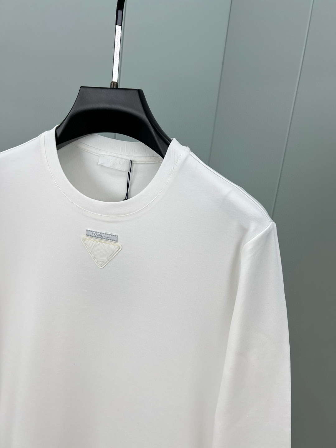  
Prada.普拉达 25秋冬新品三角形贴布徽标&缝制标签棉质长袖T恤衫，正面领口装饰有标志性的三角形