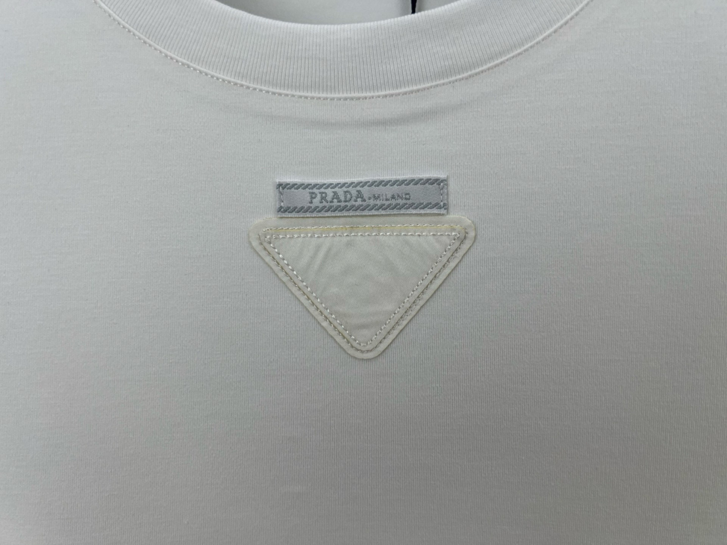  
Prada.普拉达 25秋冬新品三角形贴布徽标&缝制标签棉质长袖T恤衫，正面领口装饰有标志性的三角形