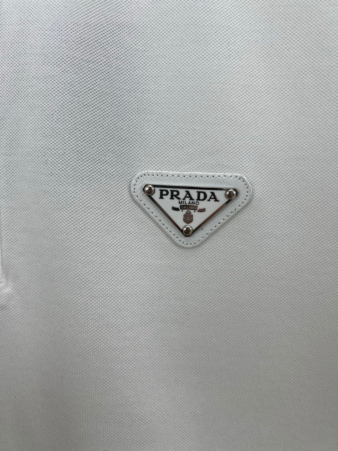 
Prada.普拉达 春夏经典涂珐琅三角形金属徽标Polo衫，正面胸前缀饰涂珐琅三角形金属徽标为时尚设计