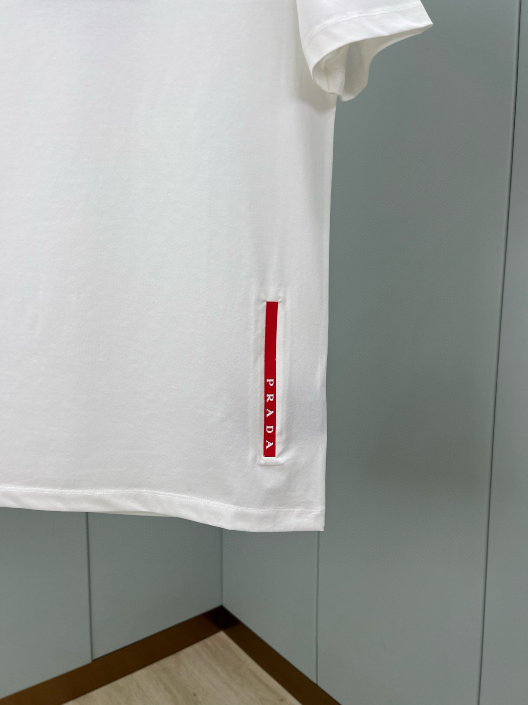 Prada.普拉达 春夏经典标志性的涂珐琅倒三角五金皮章短袖T恤，正面领口处下饰以品牌标志性的涂珐琅三角