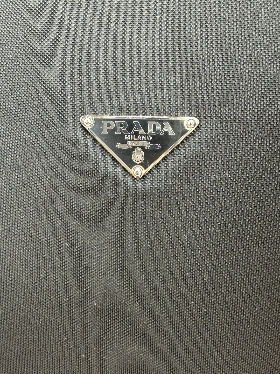 Prada.普拉达 SS26春夏新品经典标识涂珐琅金属三角形徽标Polo衫，以最简约的形式呈现，体现了休