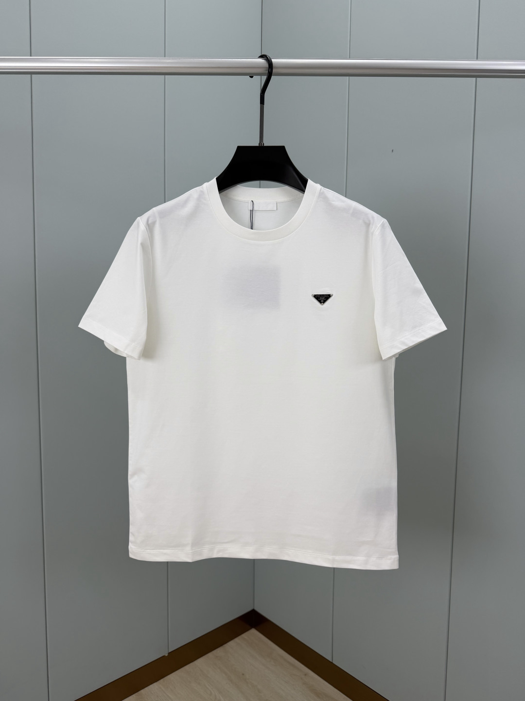 Prada.普拉达 SS26春夏新品经典标识涂珐琅金属三角形徽标短袖T恤，正面胸前饰有品牌经典标志性三角