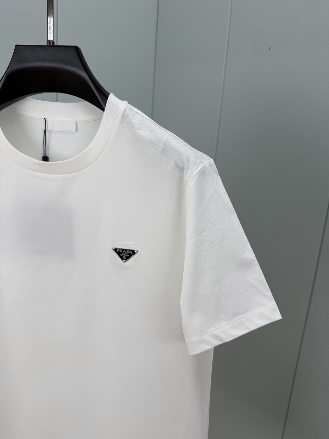 Prada.普拉达 SS26春夏新品经典标识涂珐琅金属三角形徽标短袖T恤，正面胸前饰有品牌经典标志性三角