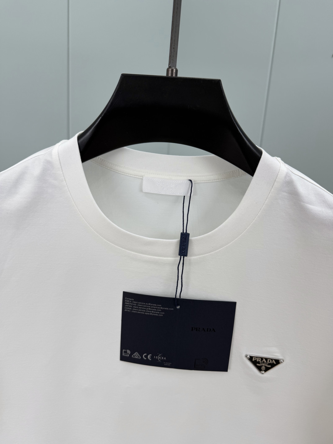 Prada.普拉达 SS26春夏新品经典标识涂珐琅金属三角形徽标短袖T恤，正面胸前饰有品牌经典标志性三角