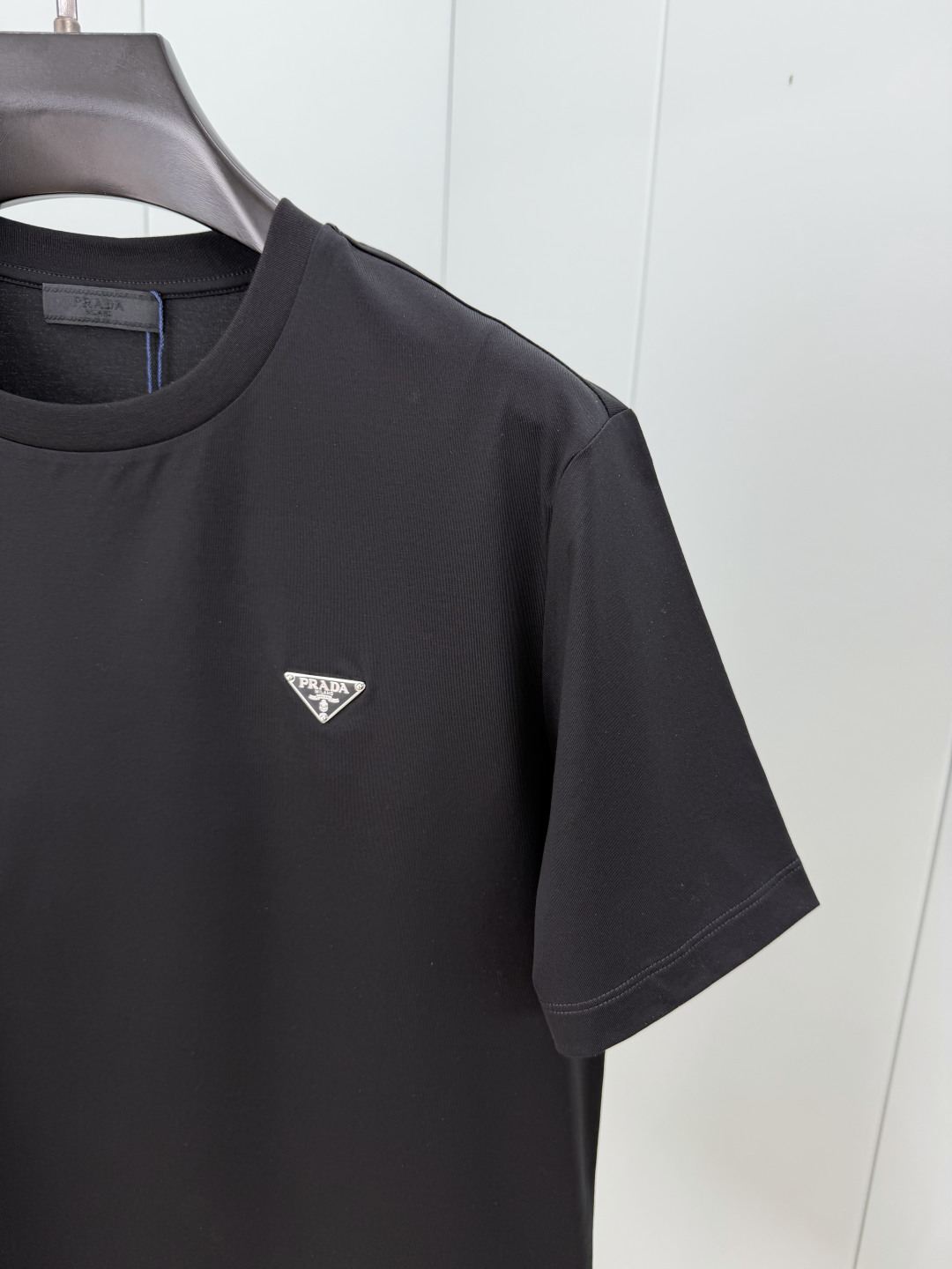 Prada.普拉达 SS26春夏新品经典标识涂珐琅金属三角形徽标短袖T恤，正面胸前饰有品牌经典标志性三角