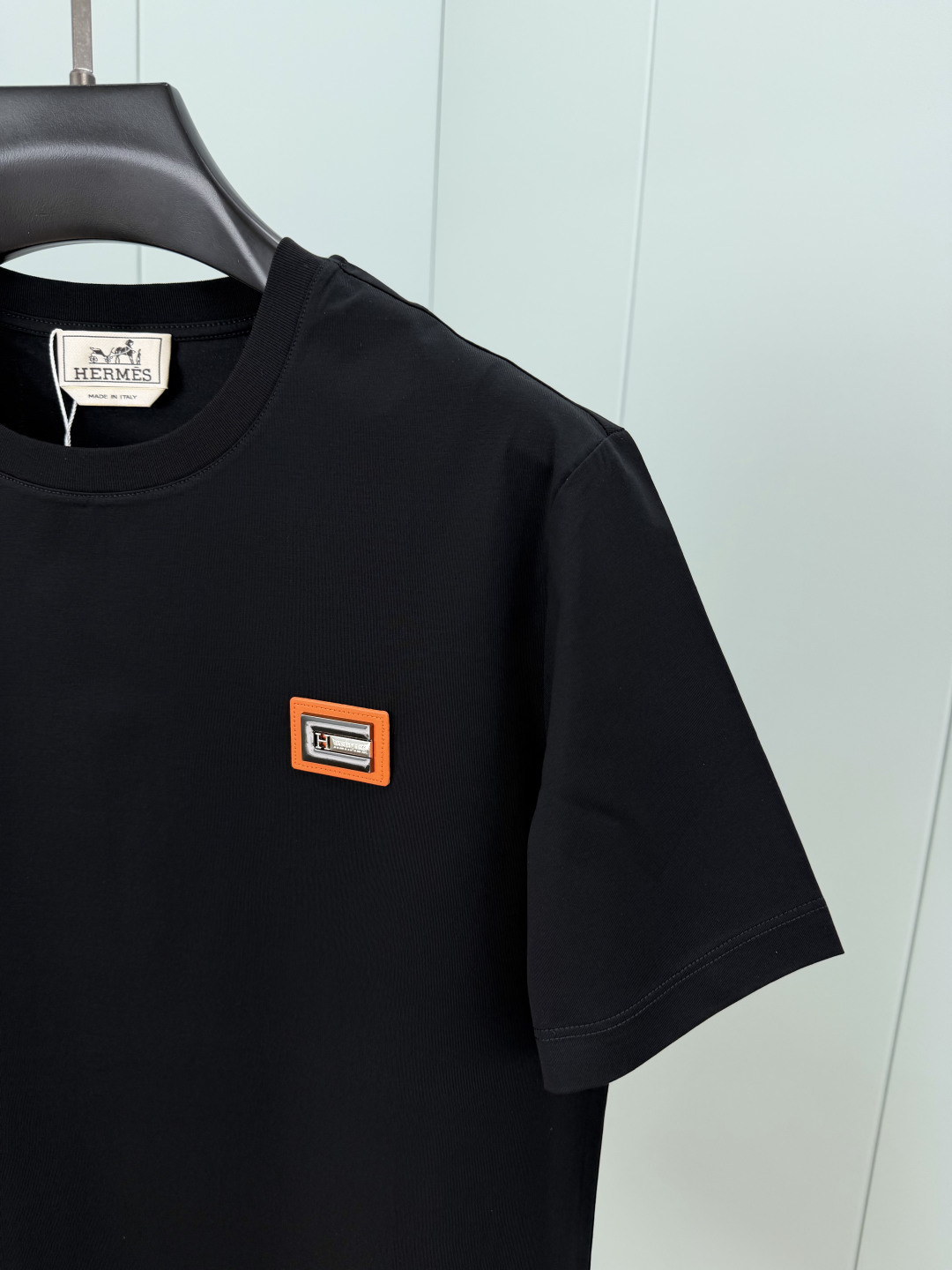 Hermès.爱马仕 SS26春夏新品品牌字母五金皮革徽章短袖T恤，正面胸前饰橙色皮革+品牌字母五金组合