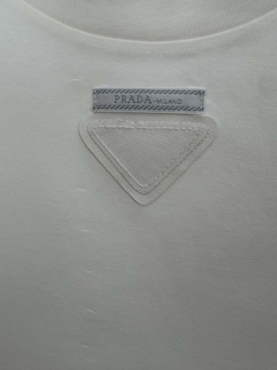 Prada.普拉达 SS26春夏新品三角形贴布徽标&缝制标签短袖T恤，正面领口装饰标志性的三角形徽标几何