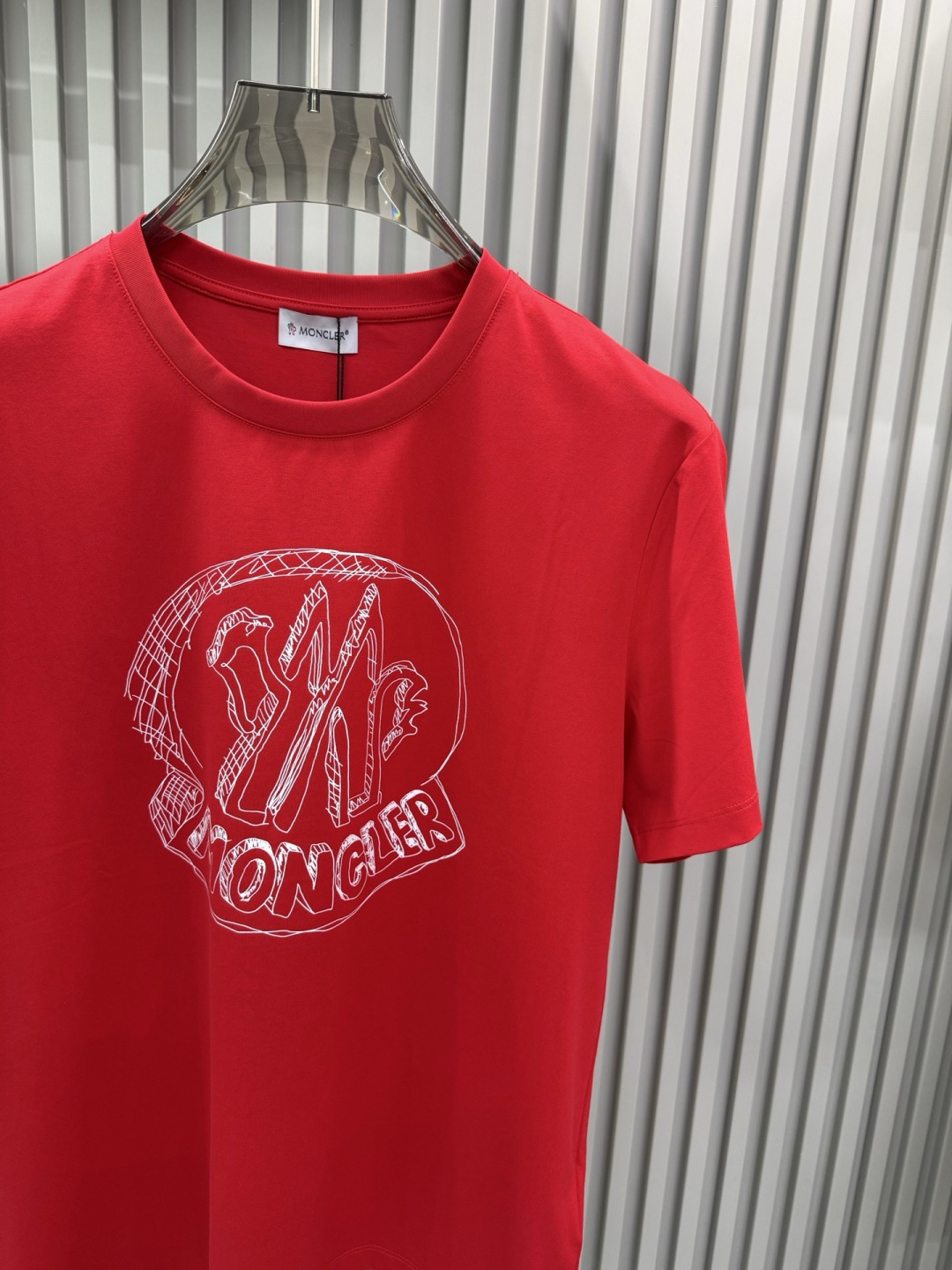 Moncler2026春夏新品抽象印花圆领短袖T恤，主打简约时髦与品牌辨识度的结合。正面采用白色手绘风格