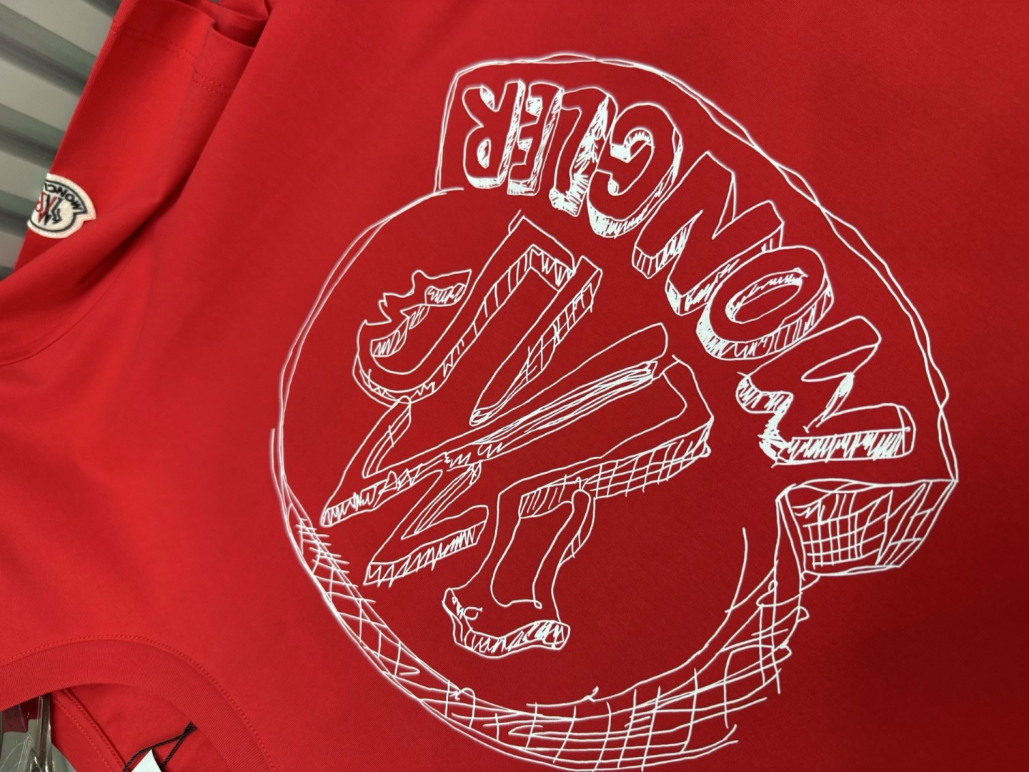Moncler2026春夏新品抽象印花圆领短袖T恤，主打简约时髦与品牌辨识度的结合。正面采用白色手绘风格