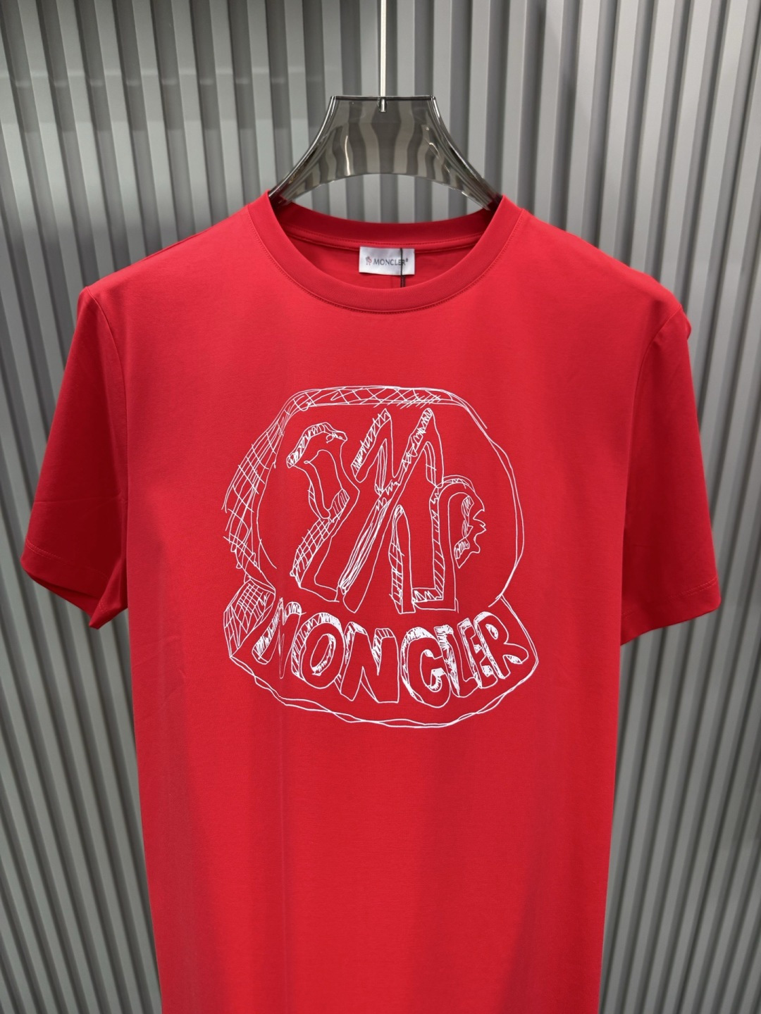 Moncler2026春夏新品抽象印花圆领短袖T恤，主打简约时髦与品牌辨识度的结合。正面采用白色手绘风格