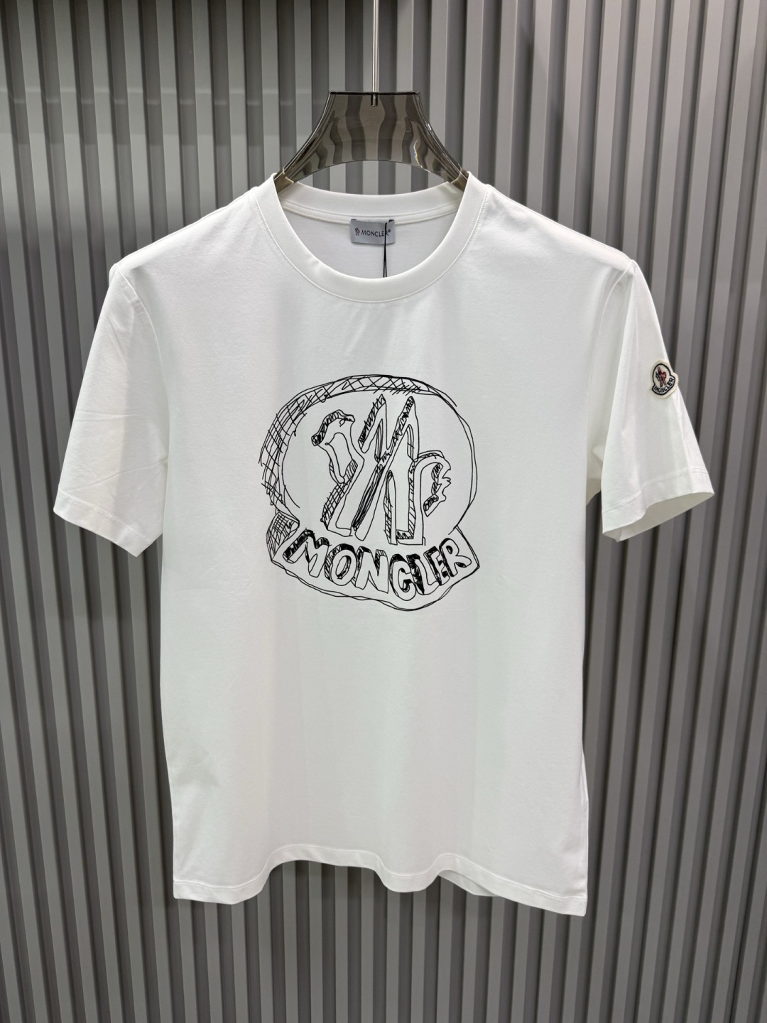 Moncler2026春夏新品抽象印花圆领短袖T恤，主打简约时髦与品牌辨识度的结合。正面采用白色手绘风格