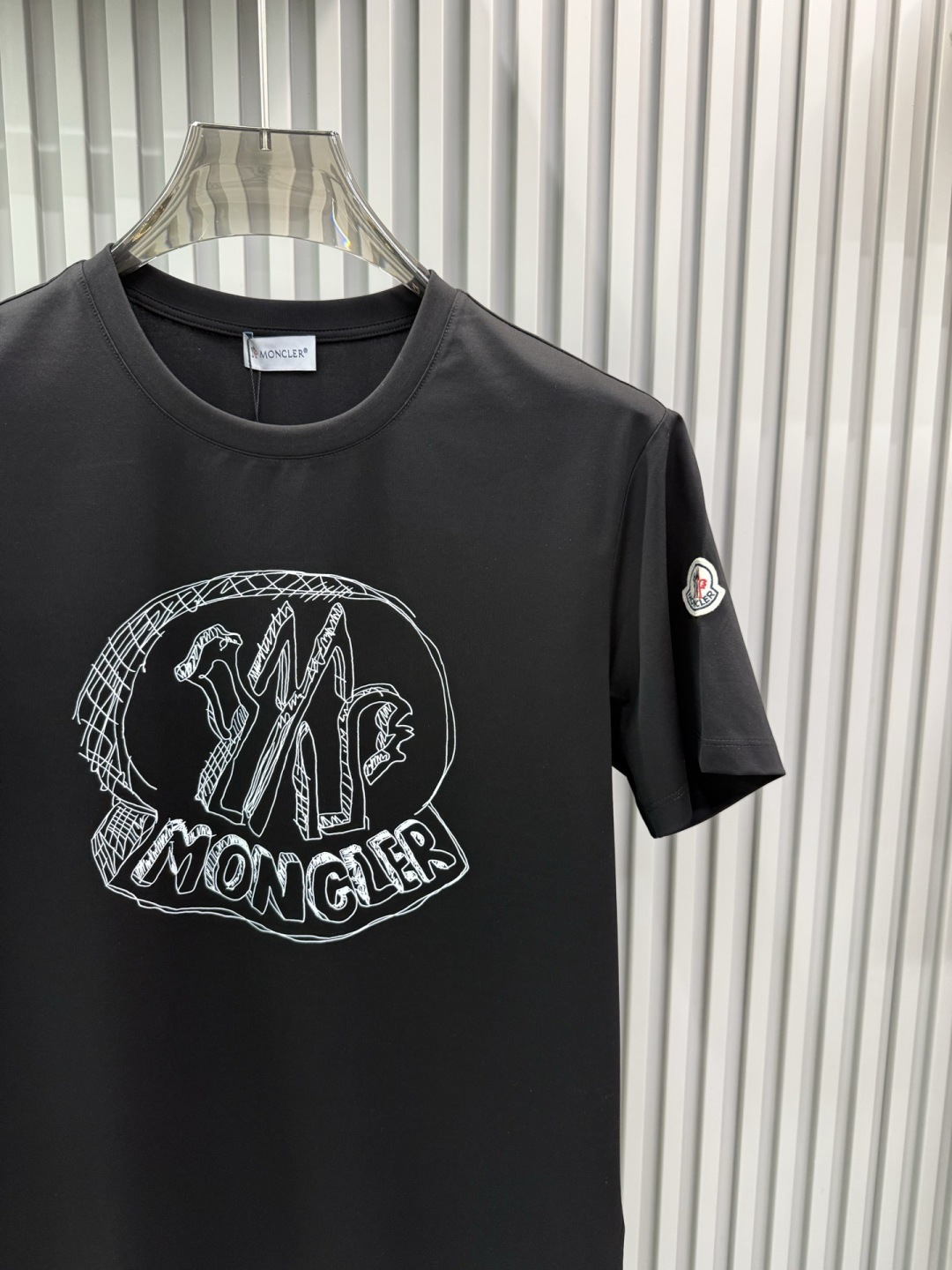 Moncler2026春夏新品抽象印花圆领短袖T恤，主打简约时髦与品牌辨识度的结合。正面采用白色手绘风格