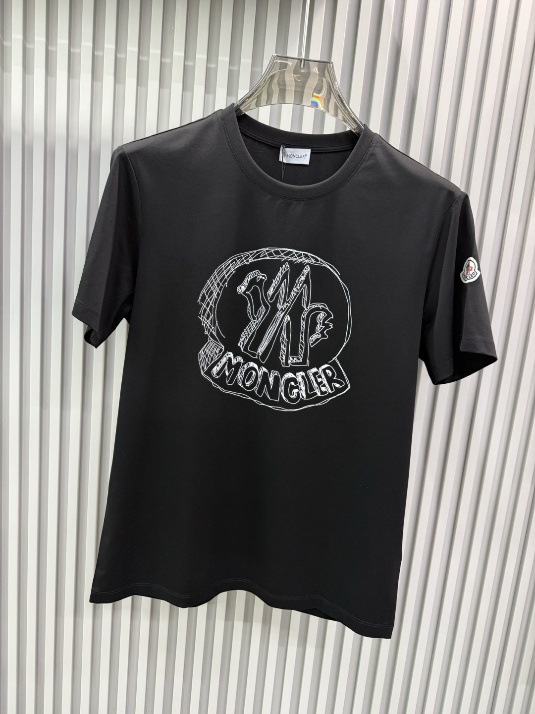 Moncler2026春夏新品抽象印花圆领短袖T恤，主打简约时髦与品牌辨识度的结合。正面采用白色手绘风格