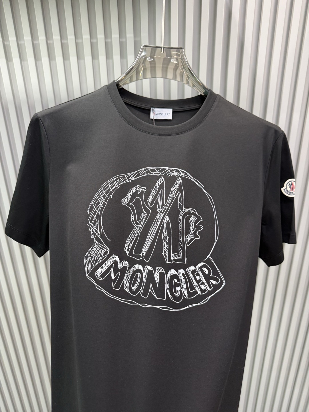 Moncler2026春夏新品抽象印花圆领短袖T恤，主打简约时髦与品牌辨识度的结合。正面采用白色手绘风格