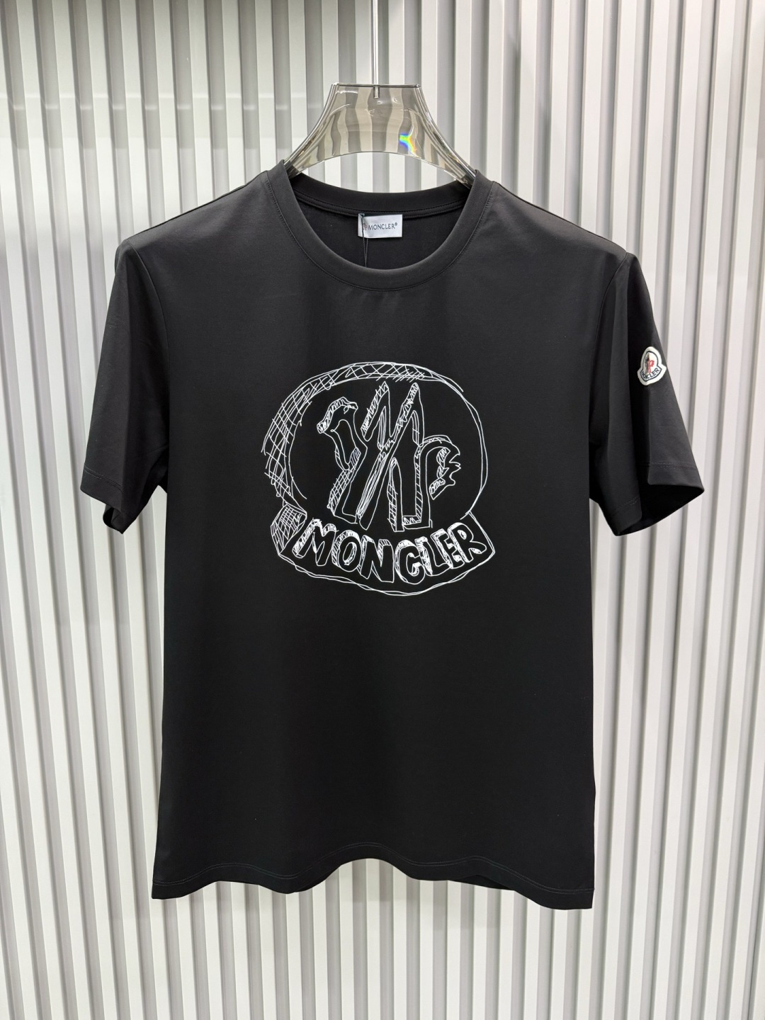 Moncler2026春夏新品抽象印花圆领短袖T恤，主打简约时髦与品牌辨识度的结合。正面采用白色手绘风格