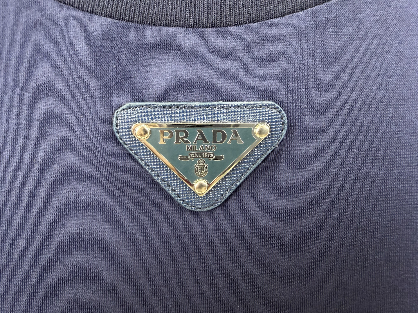 Prada.普拉达 春夏经典标志性的涂珐琅倒三角五金皮章短袖T恤，正面领口处下饰以品牌标志性的涂珐琅三角