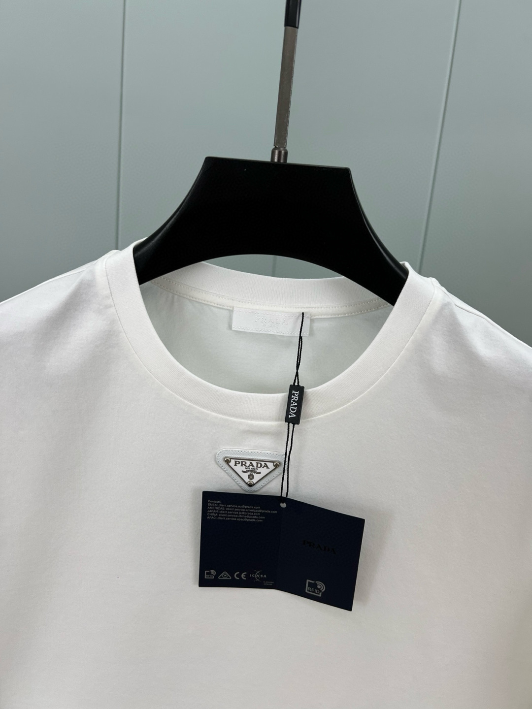 Prada.普拉达 春夏经典标志性的涂珐琅倒三角五金皮章短袖T恤，正面领口处下饰以品牌标志性的涂珐琅三角