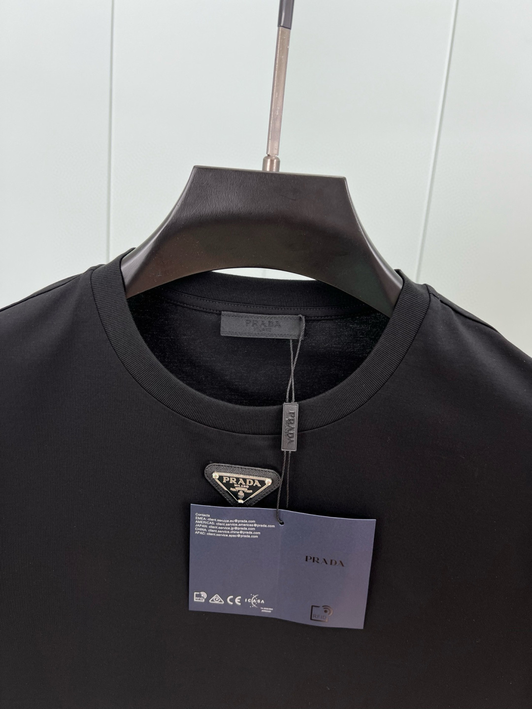 Prada.普拉达 春夏经典标志性的涂珐琅倒三角五金皮章短袖T恤，正面领口处下饰以品牌标志性的涂珐琅三角