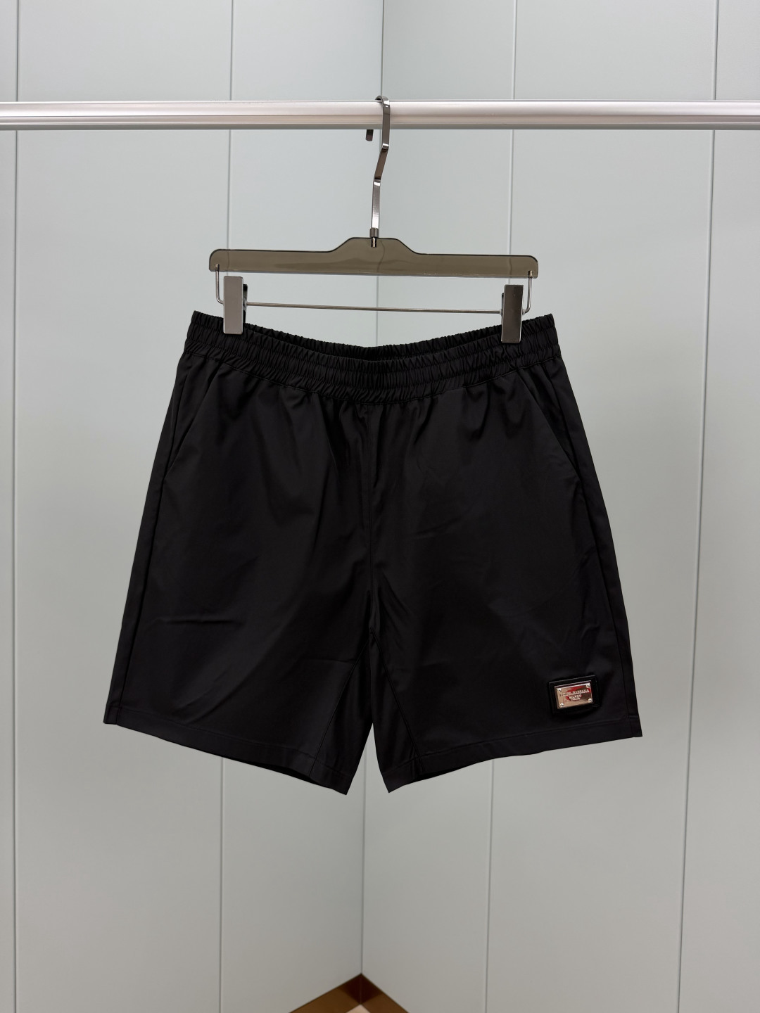 Dolce&Gabbana.杜嘉班纳 夏季经典金属皮牌徽标再生尼龙四分休闲短裤，正面左侧下摆饰有品牌经典