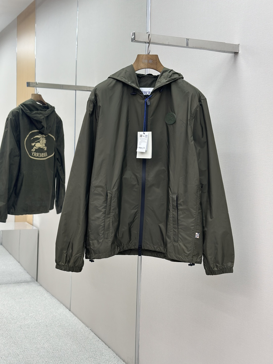 NO:954801,BURBERRY Knight's Seal Hooded Jacket  Process description: Made of lightweight and wear-resistant nylon fabric, it is both comfortable and practical. The iconic B-shaped zipper puller highlights the brand's genes, and the two-way zipper design is easy to put on and take off. Both the hood and the hem are equipped with drawstrings to freely adjust the tightness. The side zipper pockets provide safe storage space, and the elastic cuffs ensure a good fit on the wrist. The back uses a screen printing process to present the brand's collection of knight prints.  The chapter pattern is inspired by the bag design in the 1980s. The sleeves are embellished with EKD equestrian knight logo silicone plaques, and the details show the brand's equestrian genes. The overall fit is casual, which is looser and more comfortable than the regular fit. It comes with a special dust bag for easy storage and maintenance. This jacket perfectly combines the brand's classic elements with modern functionality, making it an urban leisure item that is both fashionable and practical.  SizeM-3XL,,burberry,jackets & coats,jackets & coats,hats,19860909BURBERRY骑士印章连帽夹克外套 工艺说明采用轻盈耐磨的尼龙面料精制而成,兼具舒适性与实用性.标志性的B字型拉链头彰显品牌基因,双向拉链设计便于穿脱.连帽和衣摆均配有抽绳,可自由调节松紧度.侧边拉链口袋提供安全储物空间,弹性袖口确保贴合手腕.背部采用丝网印花工艺呈现品牌典藏的骑士印章图案,灵感源自1980年代包款设计.衣袖处点缀EKD马术骑士徽标硅胶饰牌,细节处展现品牌马术基因.整体采用休闲版型剪裁,比常规版型更为宽松舒适.随附专用防尘袋便于收纳保养.这款夹克将品牌经典元素与现代功能性完美结合,是兼具时尚与实用的都市休闲单品. SizeM-3XL,,burberry,jackets & coats,jackets & coats,hats,,Men's clothing