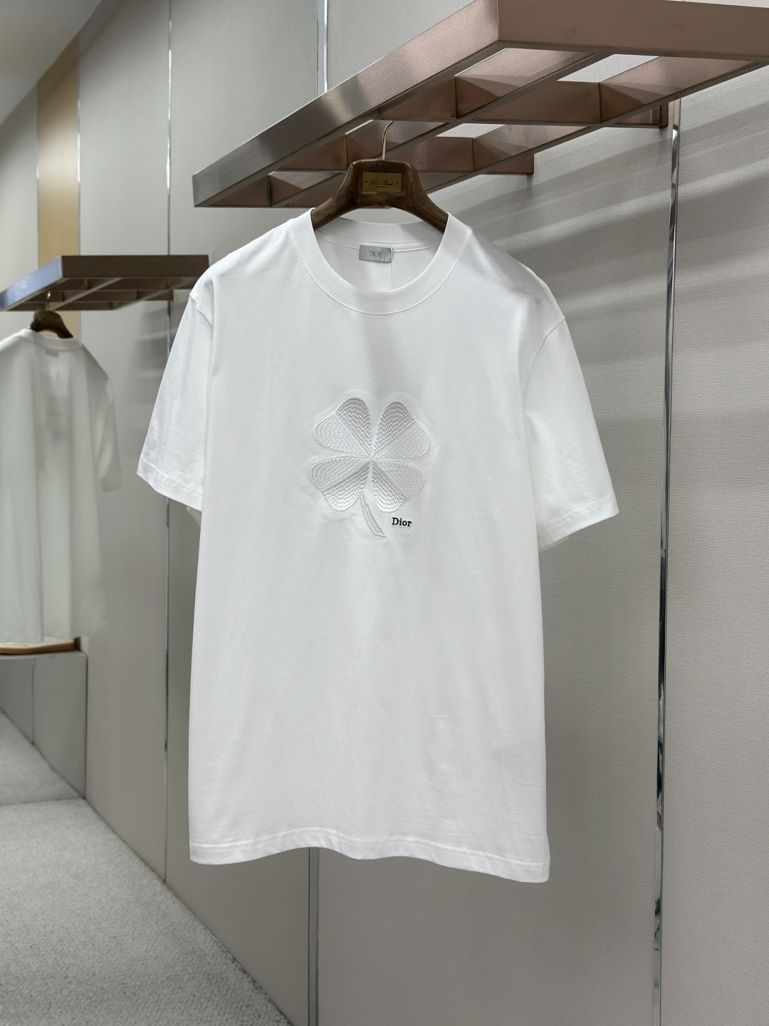 NO:857344,DIOR's 2026 spring and summer new T-shirt is presented in a classic round-neck short-sleeved style. The chest is decorated with a delicate four-leaf clover embroidery pattern, with the 'B' letter logo at the top, the 'BAIRMAN' word in the center and the brand name below, using delicate craftsmanship to highlight the three-dimensional texture and lucky meaning. The overall design combines romantic symbols with contemporary aesthetics, continuing the brand's exquisite skills. The simple style contains exquisite details, perfectly balancing the casual and luxurious charm. Whether it is paired with jeans to create an everyday casualness  look, or combined with a skirt to attend a casual party, it can be the finishing touch of the style, interpreting Dior's unique romantic poetry and fashion attitude. Sizes M-XXXL, dior, dior, skirts, jeans, T-shirt, tees, t-shirt,19860909DIOR 2026春夏新品T恤 以经典圆领短袖款式呈现.胸前饰有精致的四叶草刺绣图案,搭配上方“B”字母标识、中央“BAIRMAN”字样及下方品牌名称,以细腻工艺凸显立体质感与幸运寓意.整体设计将浪漫符号与当代美学相结合,延续品牌精湛技艺.风格简约中蕴含精致细节,完美平衡休闲感与奢华韵味.无论是搭配牛仔裤营造日常随性 look,或与半裙组合出席休闲聚会,皆能成为造型点睛之笔,诠释迪奥独有的浪漫诗意与时尚态度. 尺码M-XXXL,,dior,dior,skirts,jeans,T-shirt,tees，t-shirt,,Men's clothing