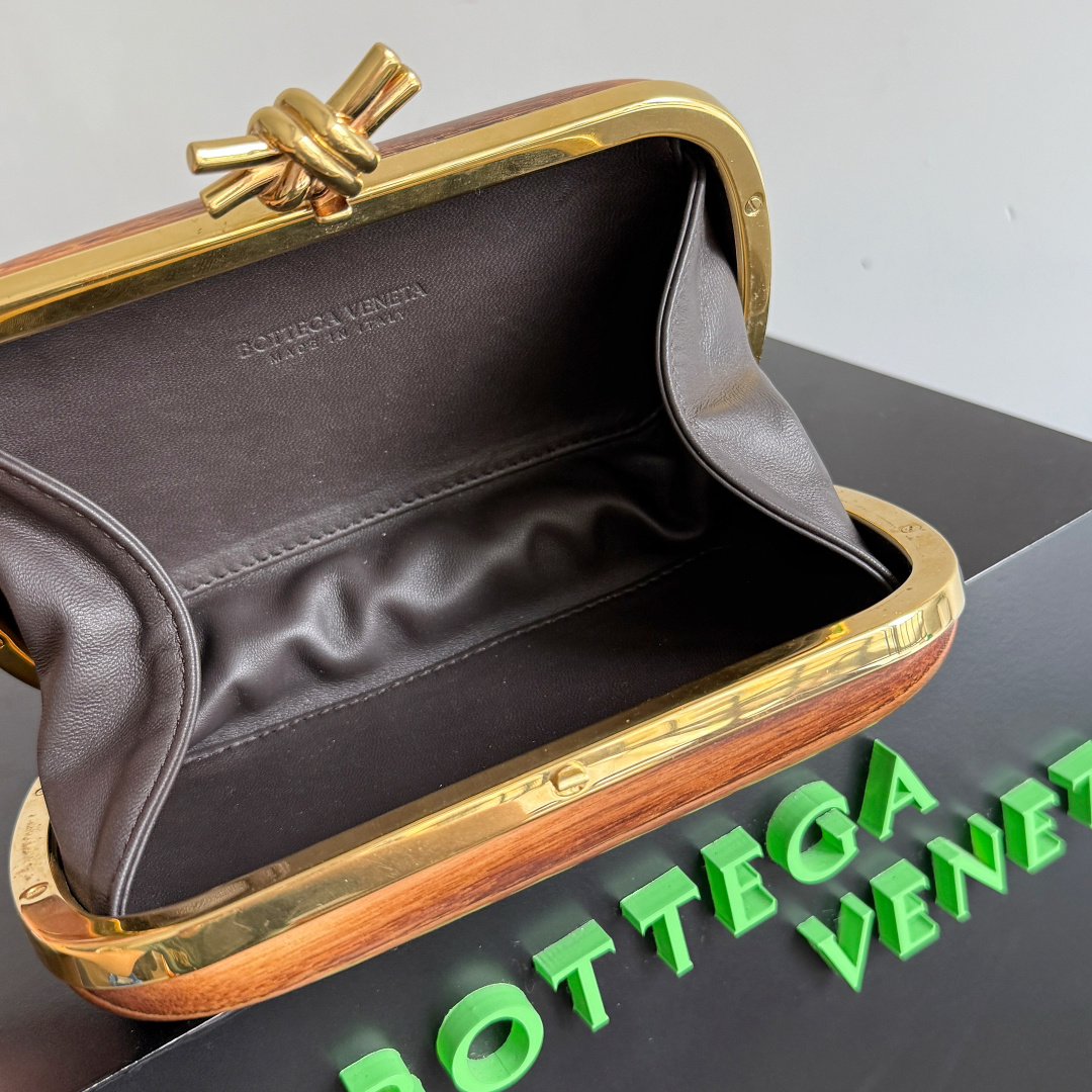 BOTTEGA VENETA2025 New Kont Banquet PackageWhen the natural texture of wood meets the brass edging, the BV dinner bag becomes a work of art in the fashion industry, with every grain of wood being a mark of time, delicate and unique. The brass metal buckle is adorned with starlight, creating a sense of ceremony when opened. It is the focus of the dinner party, able to easily store your exquisite small items. The warmth of the wood and the coolness of the metal collide, telling a niche and luxurious style in every gesture, allowing you to bloom with unique charm in every feast.Style number: 804292 (717622)Color: ChestnutSize: 20.5 * 6 * 12.5cm photo 1
