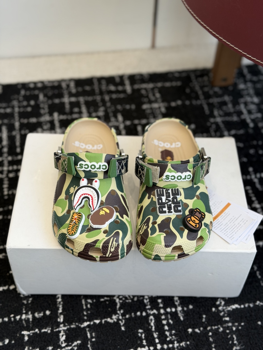 NO:758287,Purchasing-grade BAPE  CAMO camouflage pattern, black and gray, blue and white, military green and other multi-color camouflage intertwined, full of recognition, whether it is street bombing or daily outing, it can instantly become the focus. The exclusive Jibbitz (Jibbitz) on the upper is the finishing touch - shark mouth, ape head, tiger pattern elements, each is the soul symbol of BAPE. The detachable design allows you to DIY freely to create your own style. '*A BATHING' is printed on the heel of the detailed logo.  APE' words, 'CROCS' and 'APE NEVER NEVER APE' three-dimensional wordmarks on the Velcro straps emphasize the joint identity from sight to touch. Green, black M4 (36-37), M5 (37-38), M6 (38-39), M7 (39-40), M8 (41-42), M9 (42-43),  M10 (43-44), M11 (45-46) Blue M7, M8, M9, M10, M11 Pink M4, M5, M6, M7, slippers, slippers19860909代购级 BAPE × Crocs 联名洞洞鞋｜潮人鞋柜的终极炸场款 这双鞋,是街头潮流与舒适脚感的完美碰撞,每一处细节都在宣告它不止是一双鞋,更是行走的潮流符号. 设计美学把猿人迷彩穿在脚上 标志性迷彩鞋身采用BAPE经典ABC CAMO迷彩图案,黑灰、蓝白、军绿等多色迷彩交织,辨识度拉满,无论是街头炸街还是日常出街,都能瞬间成为焦点. 专属智必星鞋面上的智必星（Jibbitz）更是点睛之笔——鲨鱼嘴、猿人头、虎纹元素,每一个都是BAPE的灵魂符号,可拆卸设计让你自由DIY,打造专属风格. 细节标识后跟处印有「*A BATHING APE」字样,魔术贴绑带上的「CROCS」与「APE NEVER NEVER APE」立体字标,从视觉到触感都在强调联名身份. 绿色、黑色 M4（36-37）、M5（37-38）、 M6（38-39）、M7（39-40）、 M8（41-42）、M9（42-43）、 M10（43-44）、M11（45-46） 蓝色M7、M8、M9、M10、M11 粉色M4、M5、M6、M7,拖鞋,slippers,Women's Shoes