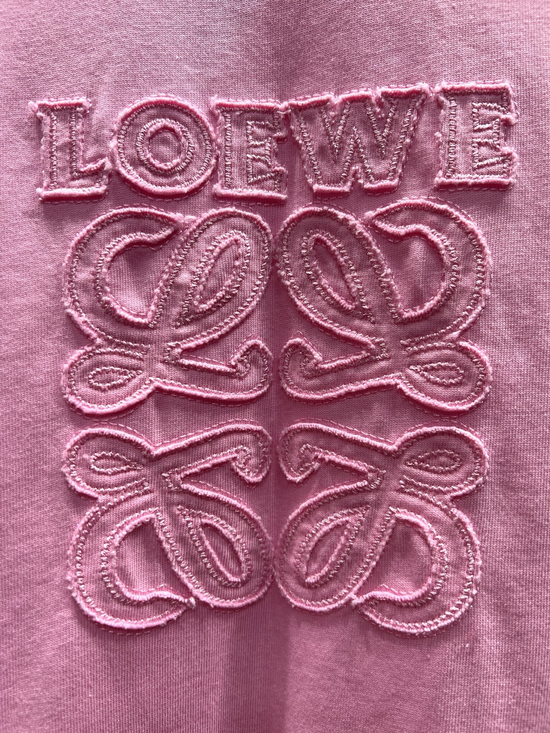 P155, Loewe*罗意威

贴布标识‼️短袖T恤®
*260g定制纯棉活性棉 面料成衣后洗水处理 手感细腻软糯 亲肤舒适。
*胸前采用贴布刺绣装饰，手感与视觉均是立体化设计 通过绲边手法让布料边缘微微隆起立体浮雕式视觉效果。
*辨识度超高的一件，自带时髦BGM，将简约玩到极致，碰撞出不一样的高阶时髦感。
⚠️洗涤方式：建议干洗或包裹洗衣袋反面单独冷水快速机洗自然晾干⚠️型号AAW66130

男女同款 
𝐂𝐎𝐋𝐎𝐔𝐑：粉色 绿色 灰色
𝐒𝐈𝐙𝐄：S-Xl