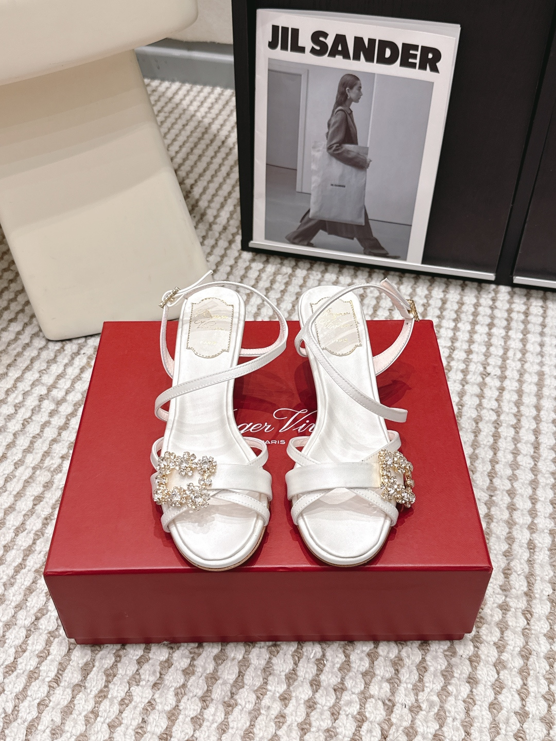 NO:781264,Purchasing agent RogerVivie*·26s spring and summer new style beautiful strappy square diamond buckle cat heel sandals  The soul of the brand, the classic square buckle, is cleverly rotated into a rhombus-shaped bevel and falls firmly on the instep. This exquisite twist instantly breaks the solemnity of the symmetry and injects a dynamic and restless modern vitality. The bright crystals or diamonds inlaid on it reflect a kaleidoscope of light under the light, making it no longer a simple logo, but a true jewel in the center of the foot, and the light becomes part of the step.  The slender leather straps wrap around the ankle in a precise geometric path. This is by no means a simple fixed function, but a visual game about nudity, wrapping and modification. Like a ballet dancer's ribbon, or the decorative engraved lines on a classical sculpture, it extremely highlights the slenderness of the ankle and the sexy lines. The straps give the sandals a custom-like sense of fit and ritual, making the act of wearing shoes itself a prelude to elegance. Roger Roger  Vivier is the inventor of the comma heel and has the highest say in heel aesthetics. The cat heel here is low, delicate and beautifully curved, which is the perfect balance of comfort and charm. It gently lifts the body posture, bringing a light and agile walk like a cat, while ensuring all-weather stability and freedom. Its shape is often like a finely carved modernist sculpture, becoming a highlight that cannot be ignored from a side perspective.  The temperament of this pair of shoes is complex and charming. With its exquisite structure and sparkling square buckle, it can not only control the elegant formal wear of high-end occasions in the daytime; but also because of its winding straps and bright light, it can become the focus of a dramatic banquet in the evening. It perfectly explains what restrained luxury is - all drama is based on classic proportions and high-end materials. Material Silk lining Sheep lining Outsole Italian imported leather outsole Shoe size 35-39/34 40 41  42 Customized, non-returnable, high heels and sandals, roger vivor, sandals, high heels, real silk, Leather soles19860909代购级 RogerVivie*·26s 春夏新款 绝美绑带斜方钻扣猫跟凉鞋 品牌灵魂——那枚经典的方形扣饰,在此被巧妙地旋转为菱形斜角,稳稳落于脚背之上.这一精妙的扭转,瞬间打破了对称的庄重,注入了一股动态的、不安分的现代活力.镶嵌其上的璀璨水晶或钻石,在光线下折射出万花筒般的光芒,使其不再是一个简单的标识,而是一枚真正意义上的足间中央珠宝,光芒成为步伐的一部分. 纤细的皮质绑带,以精密的几何路径缠绕脚踝.这绝非单纯的固定功能,而是一场关于裸露、包裹与修饰的视觉游戏.如同芭蕾舞者的缎带,或古典雕塑上的装饰刻线,极致地凸显出脚踝的纤细与线条的性感.绑带赋予了凉鞋一种定制般的贴合感与仪式感,让穿鞋的行为本身也成为一种优雅的前奏. Roger Vivier是逗号跟的发明者,对鞋跟美学有着至高话语权.这里的猫跟,低矮、精巧且弧度美妙,是舒适与风韵的完美平衡.轻轻抬升身体姿态,带来如猫咪般轻盈灵动的步履,同时保证了全天候的稳定与自在.其造型往往本身就如同一件精雕的现代主义雕塑件,成为侧面视角不容忽视的亮点. 这双鞋的气质复杂而迷人.既能凭借其精致的结构与闪耀的方扣,驾驭日间高级场合的优雅正装；又因那缠绕的绑带与璀璨的光芒,在晚间化身极具戏剧感的宴会焦点.完美诠释了何为克制的奢华——所有戏剧性都建立在经典的比例与高级的材质之上. 材质真丝 内里羊里 大底意大利进口真皮大底 鞋码35-39/34 40 41 42定制不退换,高跟鞋凉鞋,roger vivier,sandals,high heels,real silk,Leather soles,Women's Shoes